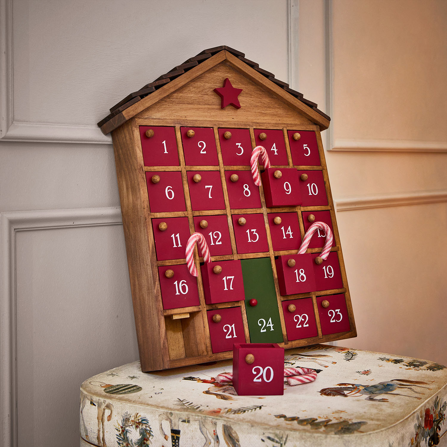 Holz-Adventskalender in Hausform mit roten Türen und grünem Türchen 24, verziert mit Zuckerstangen