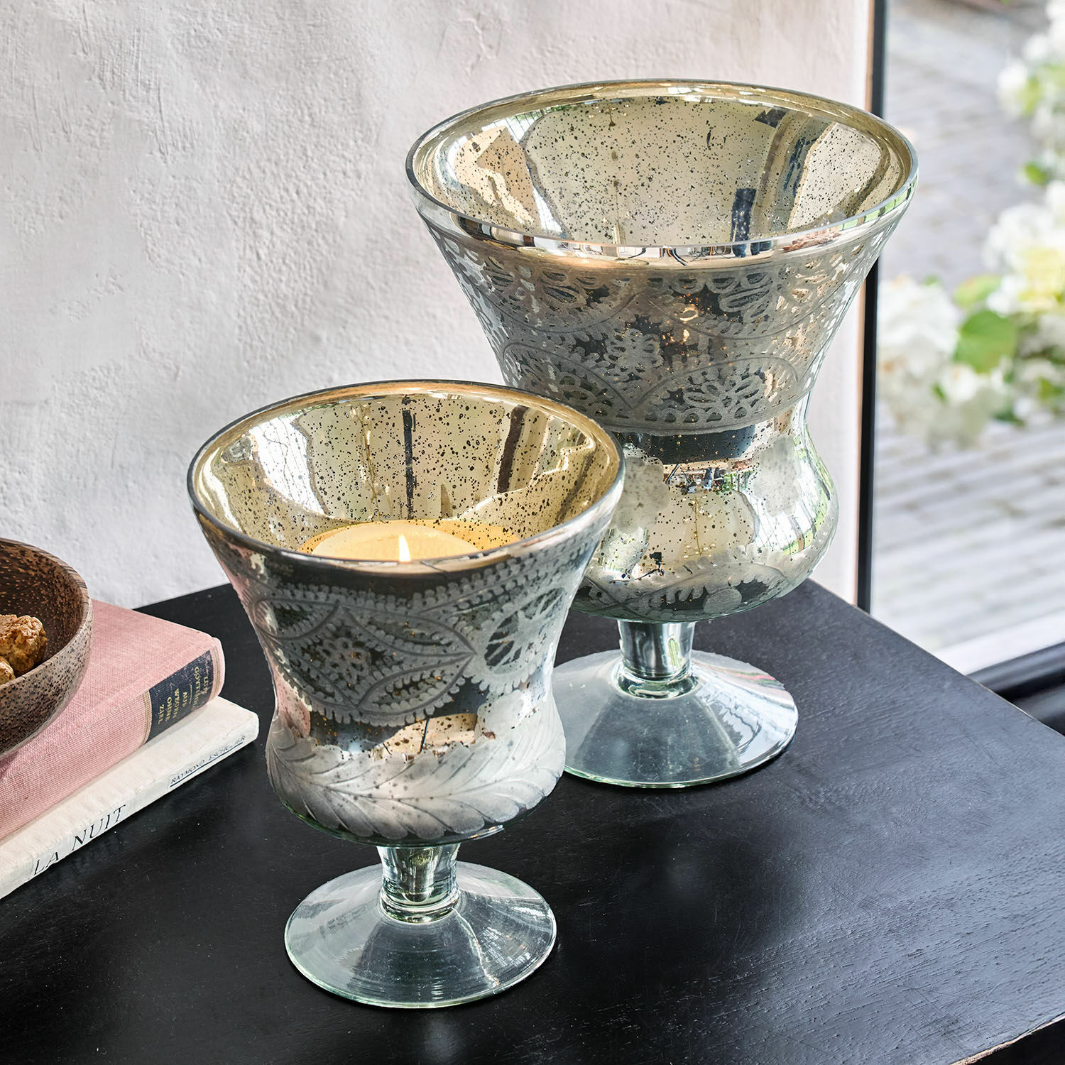Windlicht 2er Set Zorayne Zwei dekorative Glaswindlichter mit Blattmuster und silberner Oberfläche auf schwarzem Tisch