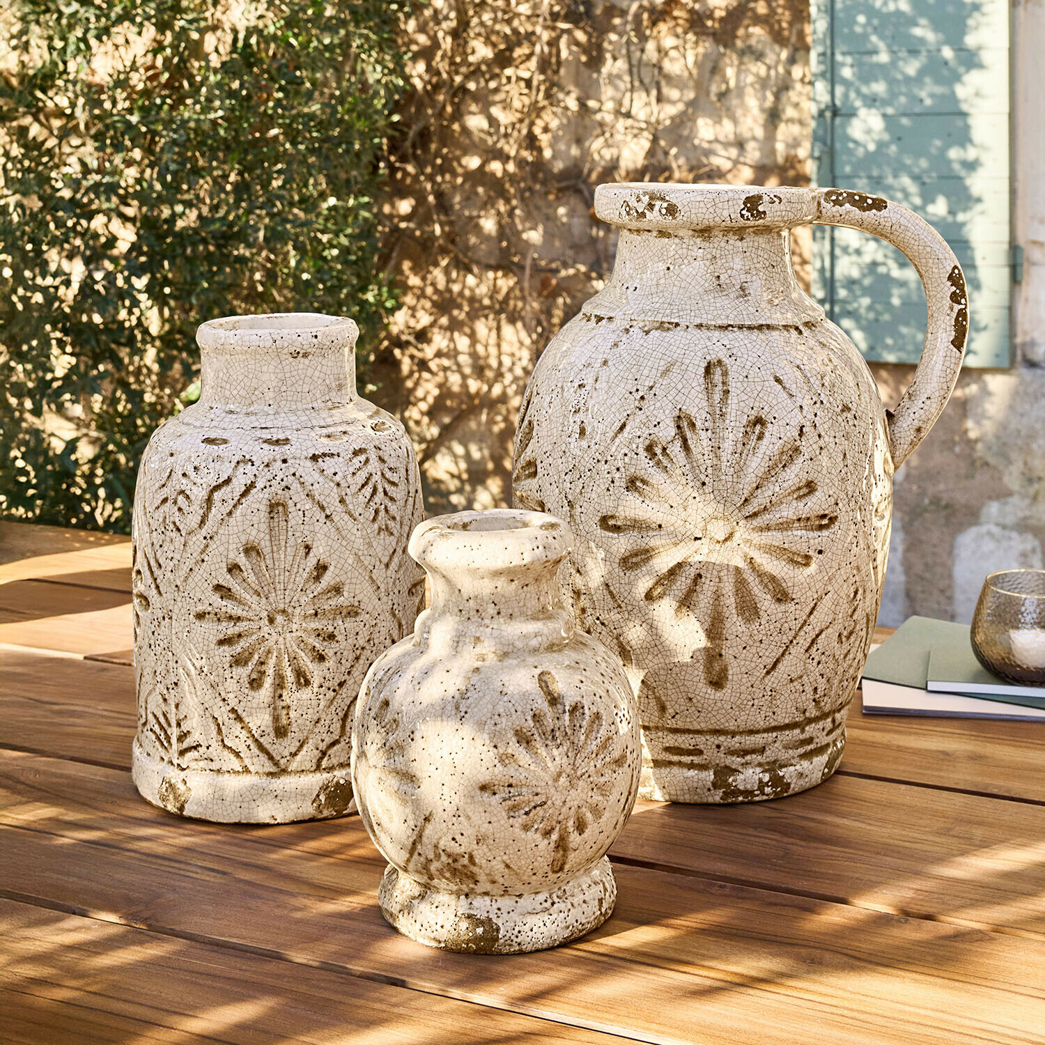 Vase 3er Set Orsémine Set mit drei cremefarbenen Keramikvasen mit braunen Mustern auf Holztisch im Freien