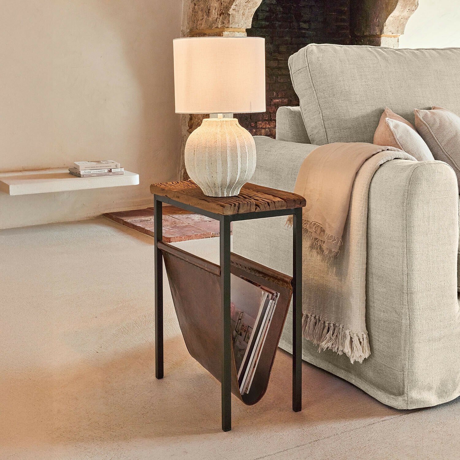 Zeitschriftenhalter Aubryn Beistelltisch mit Holzplatte und Lederfach für Zeitschriften neben beigem Sofa mit Tischlampe