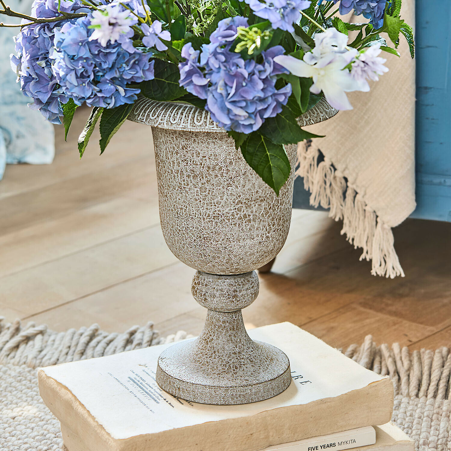 Vase Vittoriane Dekorativer beiger Keramikvase mit Patina und blauen Blumen auf alten Büchern arrangiert