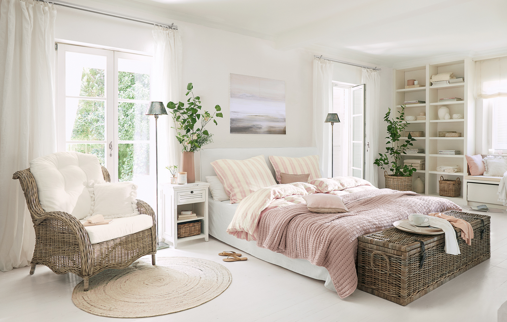 Gemütliches Landhausschlafzimmer mit Rattansessel und rosa Bettdecke