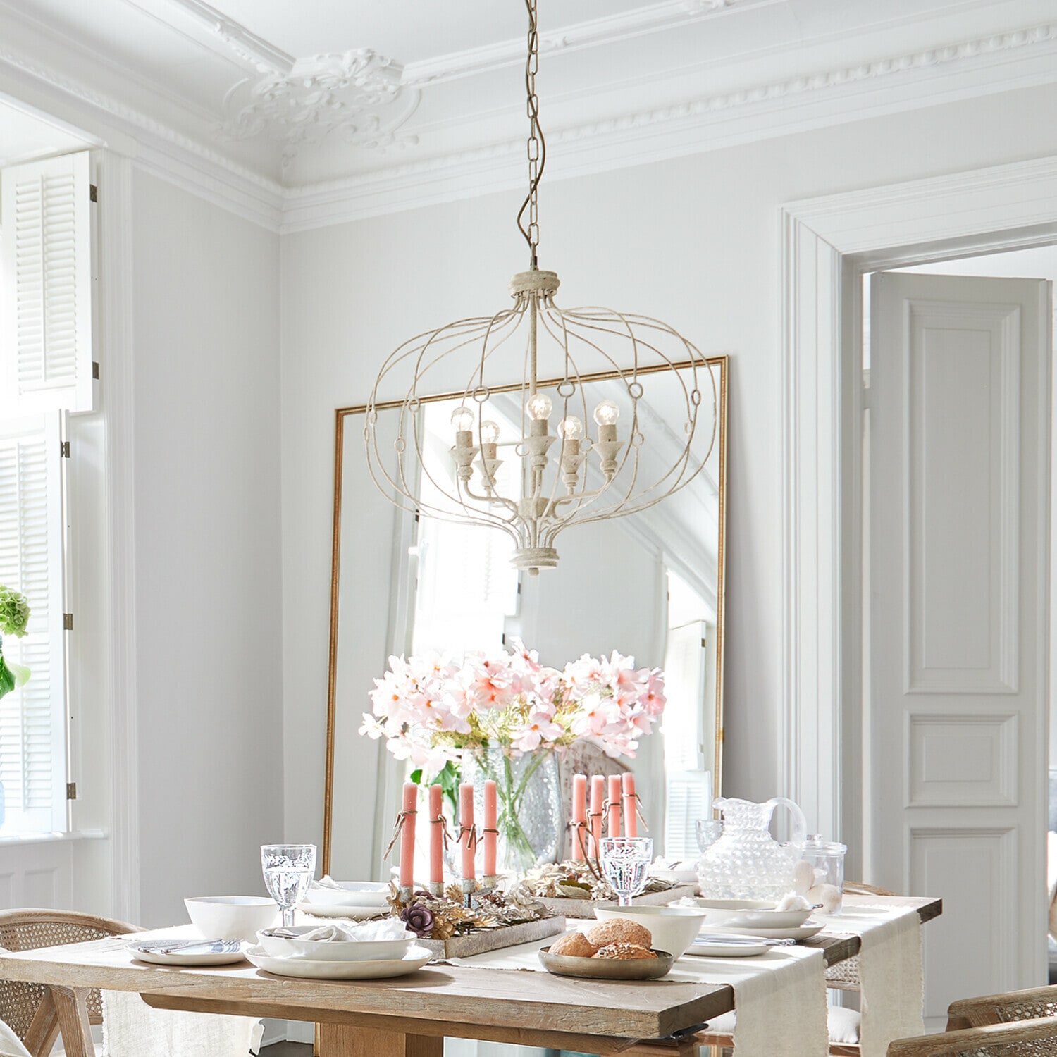 Leuchter Aragonese Helle Essecke mit Holztisch, rosa Kerzen und vintage Metall-Kronleuchter darüber