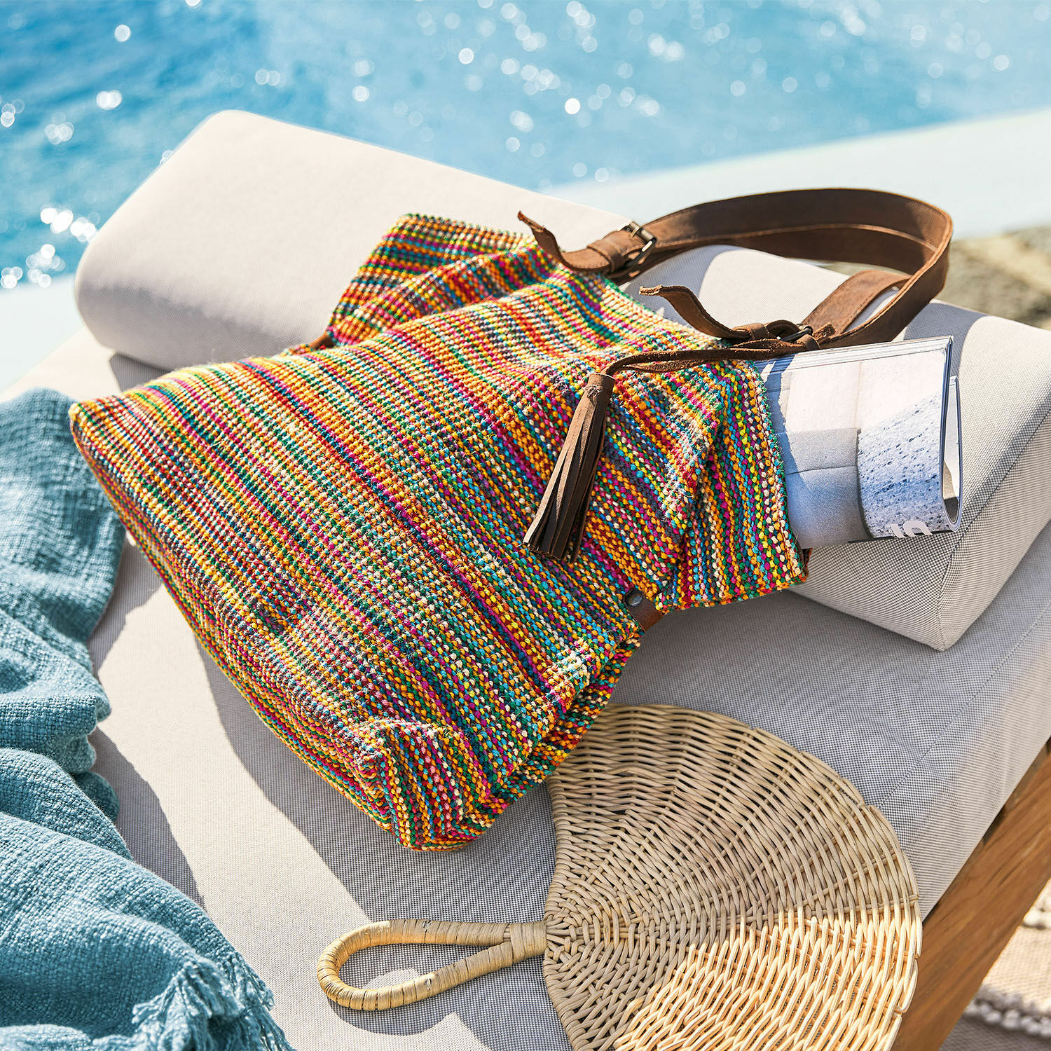 Tasche Gillian Bunte gewebte Tasche mit braunem Riemen auf hellem Liegestuhl am Pool, Sommeraccessoire
