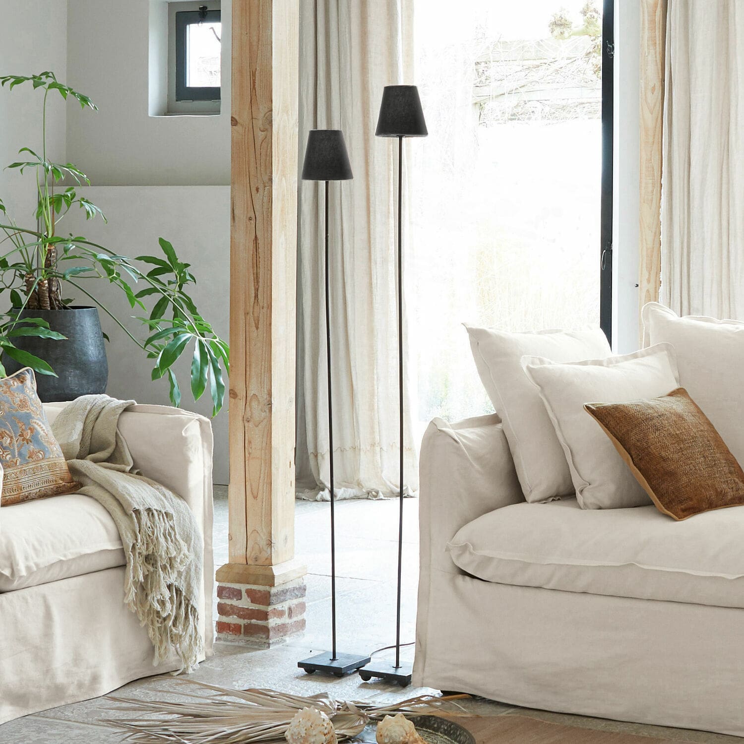 Stehlampe 2er Set Tacoma Zwei schwarze Stehlampen aus Metall im hellen Wohnzimmer mit beigem Sofa und grüner Pflanze.