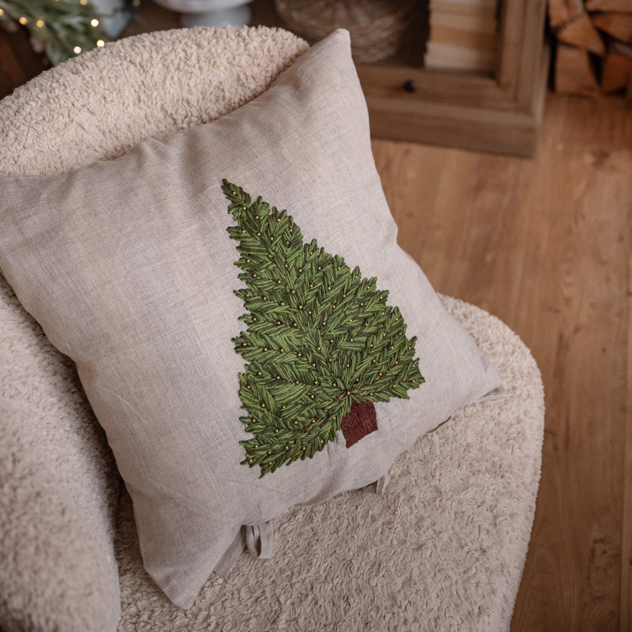 Beiges Leinenkissen mit grünem, besticktem Tannenbaum und braunem Stamm, weihnachtliche Wohnraumdeko