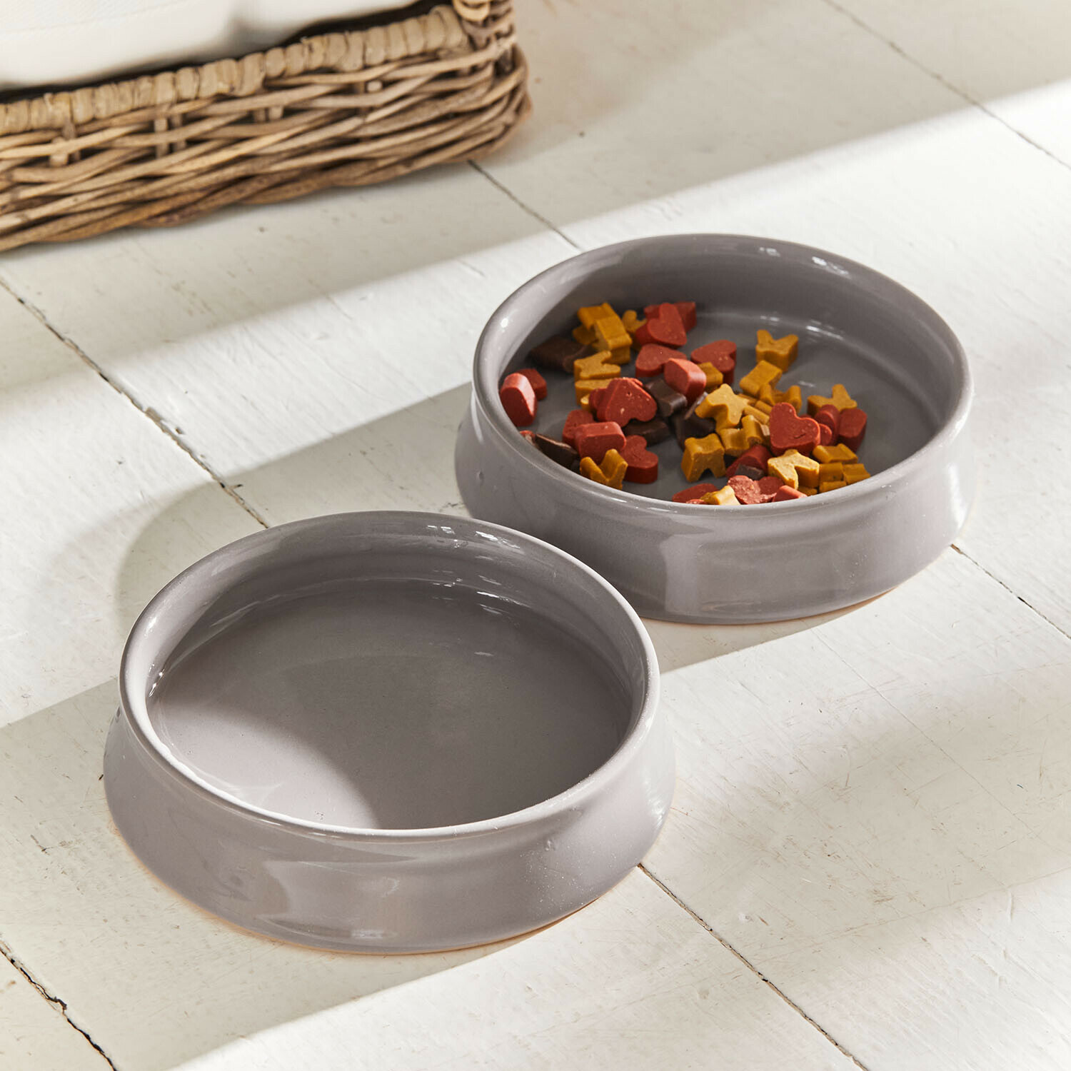 Futternapf 2er Set Hapitos Zwei graue Keramiknäpfe für Haustiere, einer mit Futter, auf weißem Holzboden