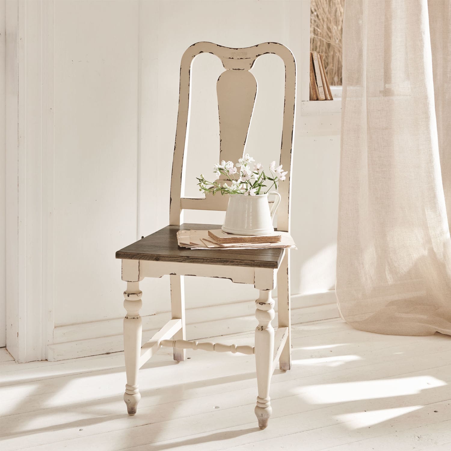 Stuhl Harry Weisser Holzstuhl im Vintage-Stil mit dunklem Sitz und Krug mit Blumen in hellem Raum