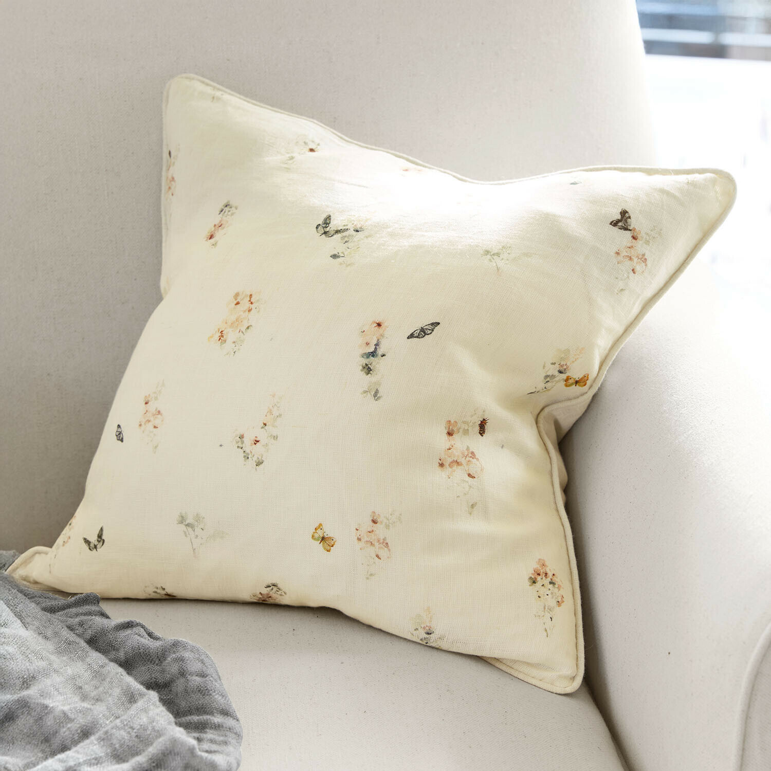 Kissenhülle Salénaïs Helles cremefarbenes Kissen mit feinem Blumen- und Schmetterlingsmuster auf Sofa, Wohnaccessoire