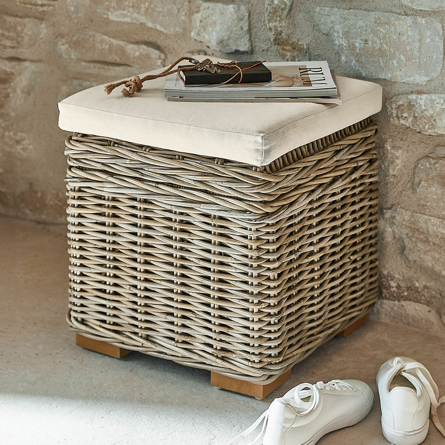 Hocker Xandrine Quadratischer grauer Korbhocker aus Rattan mit cremefarbenem Polster, ideal zum Sitzen und Verstauen.