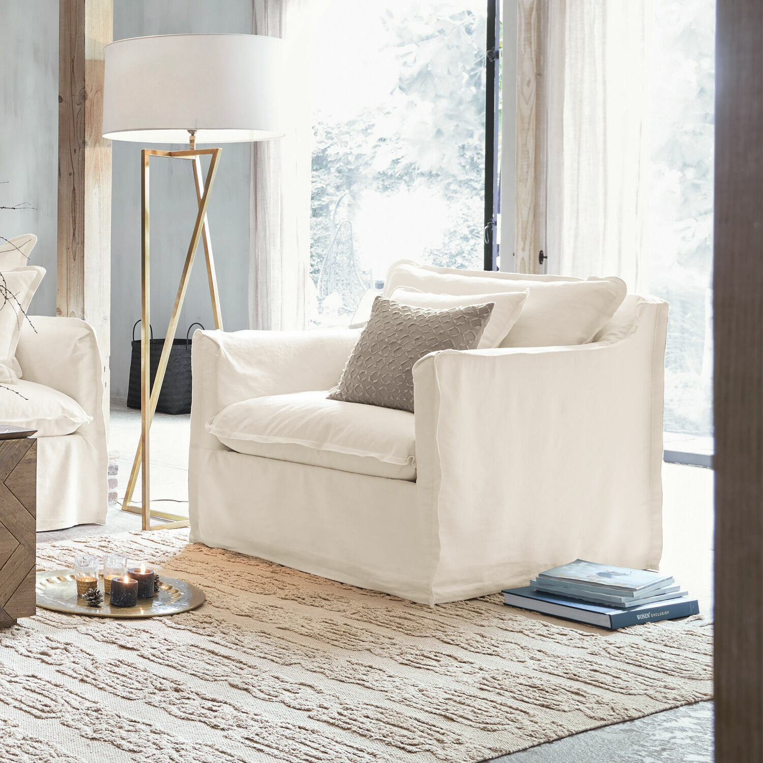 Sessel Tienen Weisser Sessel aus Stoff im hellen Wohnzimmer mit Stehlampe und Teppich, modernes Möbeldesign.