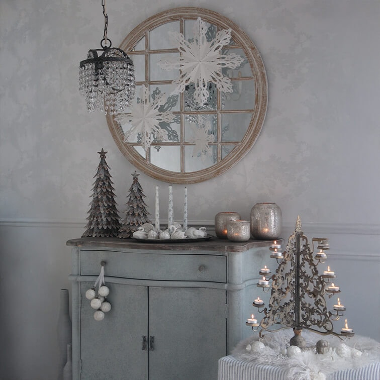 Grauer Schrank mit Weihnachtsdekoration, Metalltannenbäumen und vintage Kerzenhalter mit brennenden Kerzen