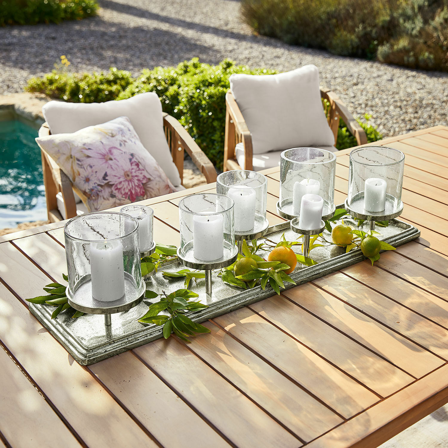 Kerzentablett Devonne Dekorativer Kerzenhalter aus Glas und Metall mit weissen Kerzen auf Holztisch im Garten