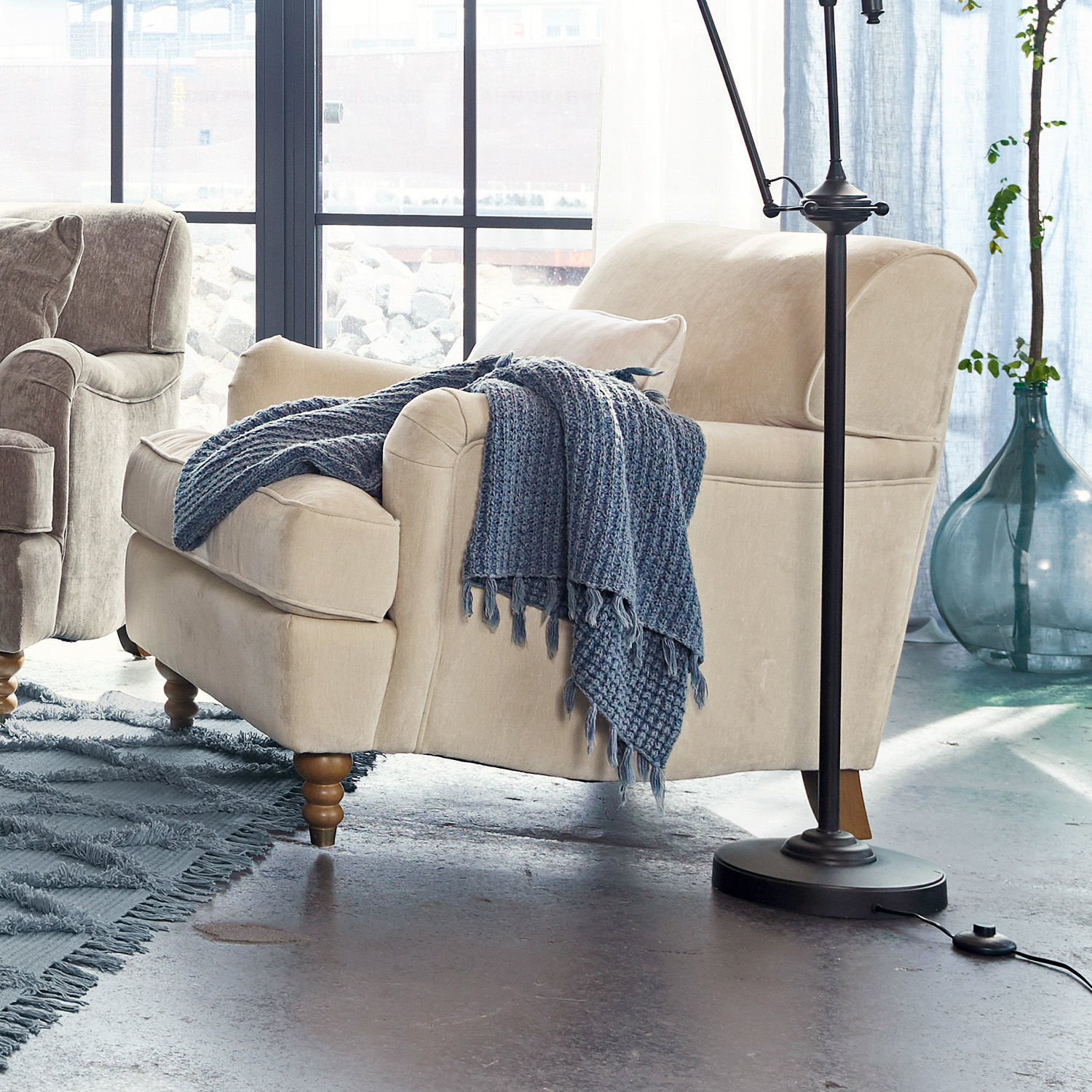 Sessel Isa Beige bezogener Sessel mit Holzbeinen und blauem Strickplaid im modernen Wohnzimmer