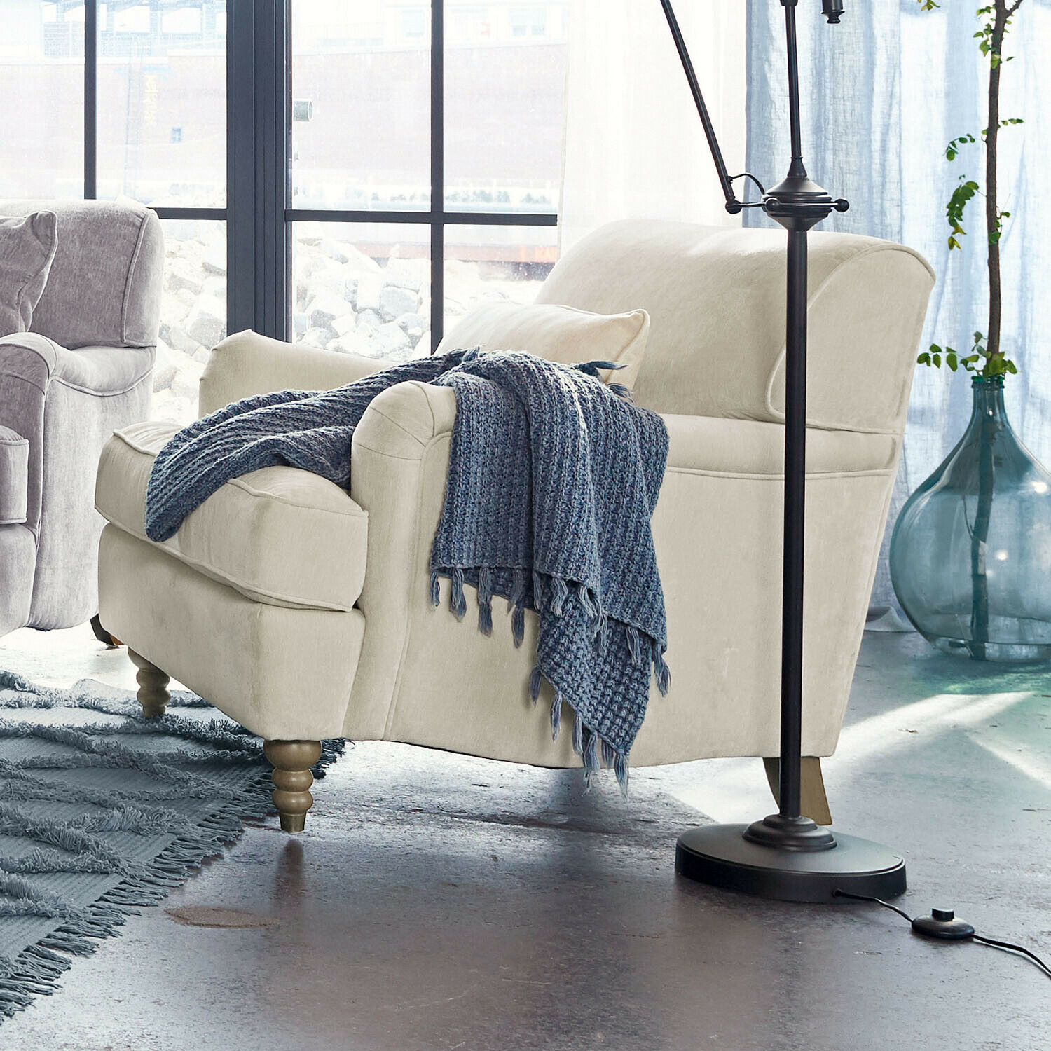 Beige bezogener Sessel mit Holzbeinen und blauem Strickplaid im modernen Wohnzimmer