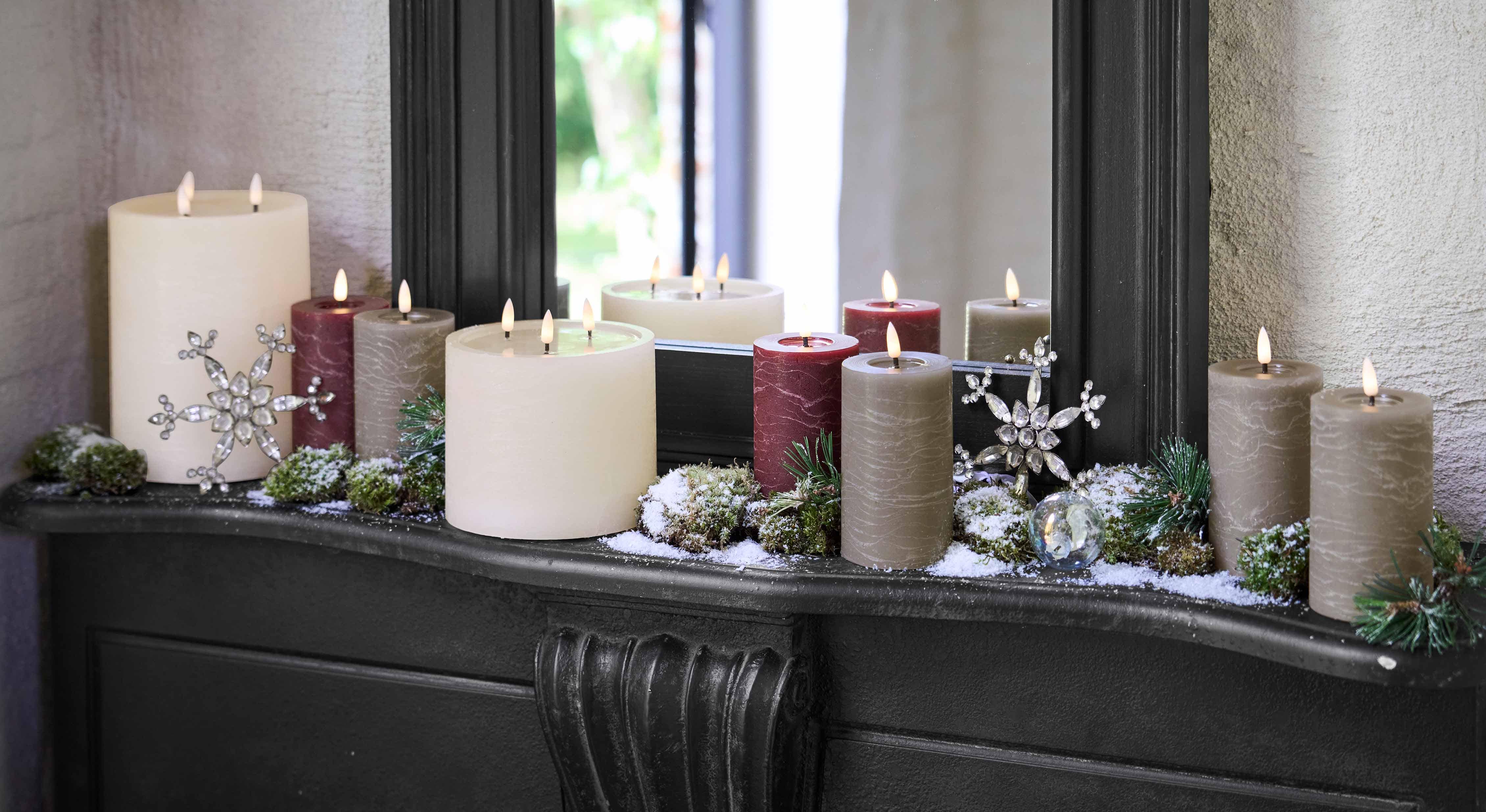 Dekoratives Kerzenset in Weiss, Bordeaux und Grau auf Kamin mit winterlichen Accessoires