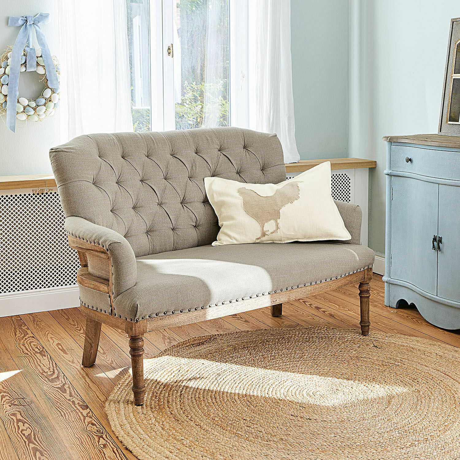 Sofa Kingsley Beiges, gepolstertes Sofa mit Holzrahmen und Zierknöpfen im hellen Wohnzimmer