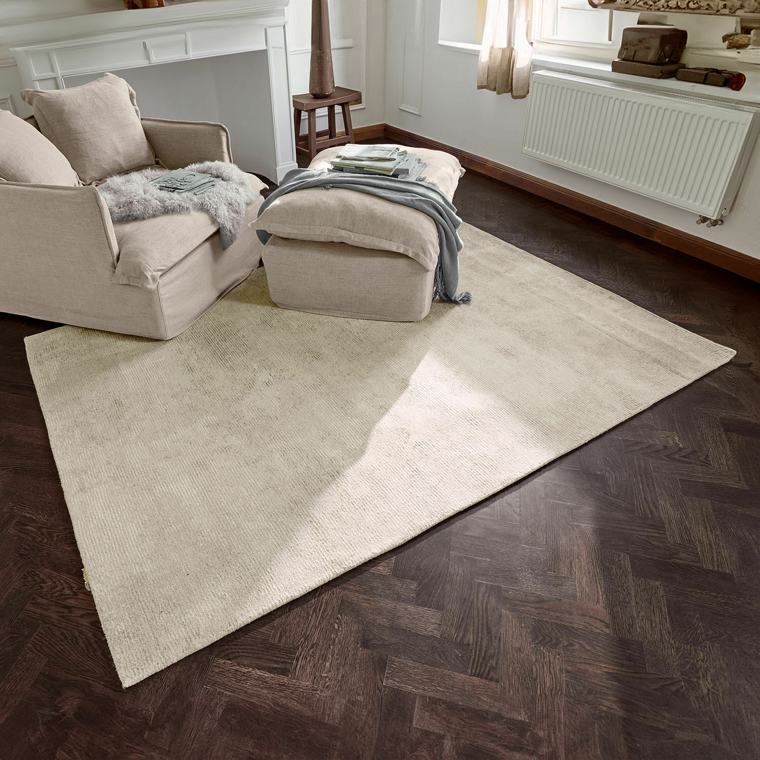 Beiger Teppich aus weichem Material auf dunklem Holzboden im hellen Wohnzimmer mit Sessel