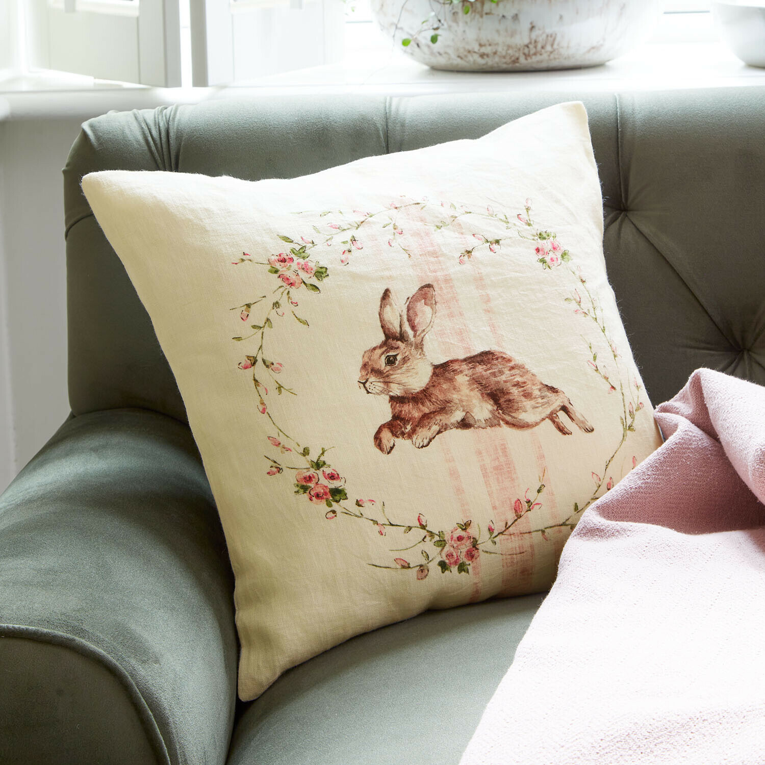 Kissenhülle Ravencrest Beiges Leinenkissen mit Hasenmotiv und rosa Blumen auf grünem Sofa mit rosa Decke