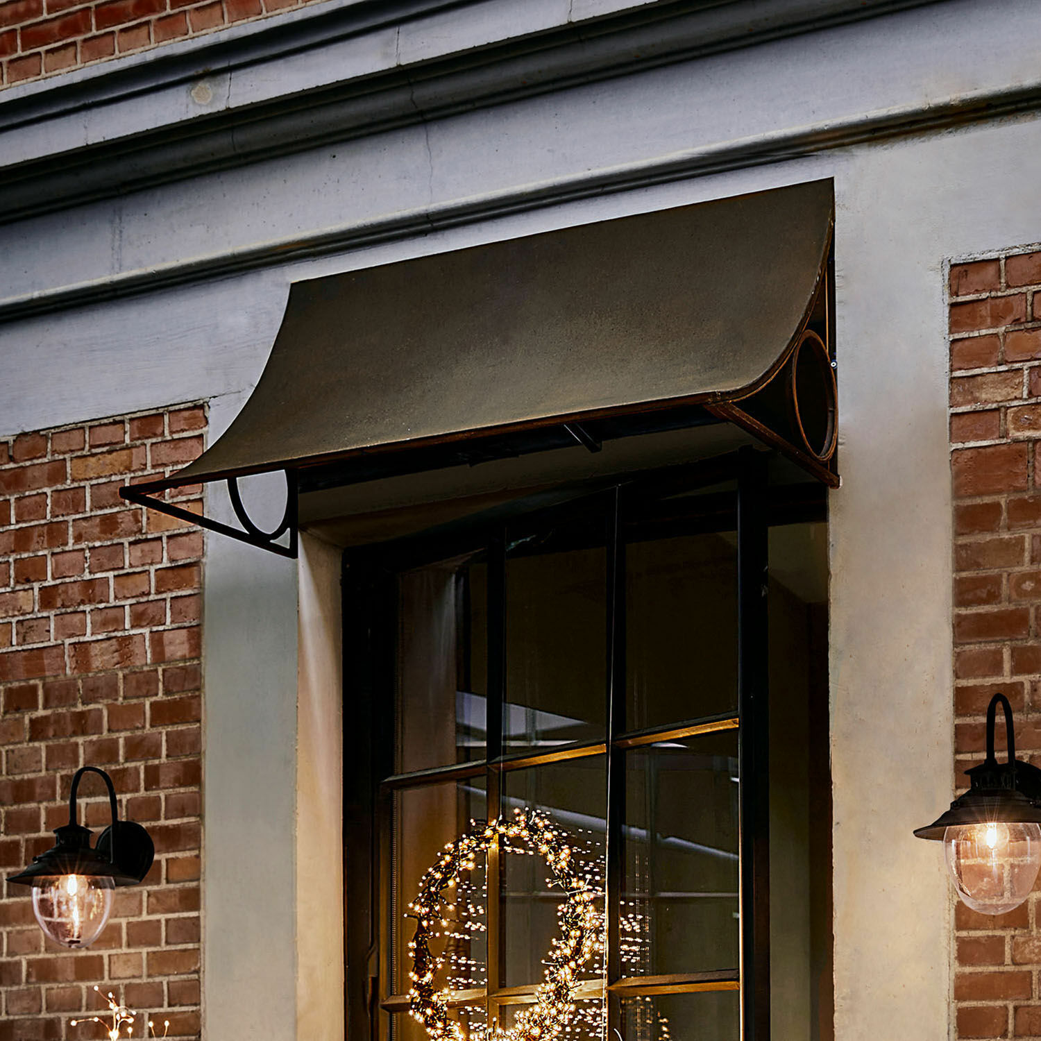 Olivgrünes Metallvordach über schwarzem Fensterrahmen mit schwarzen Aussenlampen