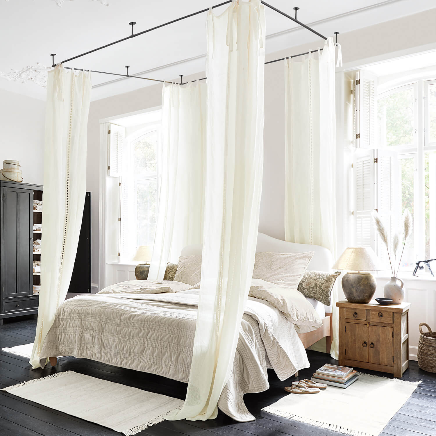 Schlafzimmer mit Himmelbett und cremefarbenen Vorhängen, Naturstoffe und helle Holzmöbel
