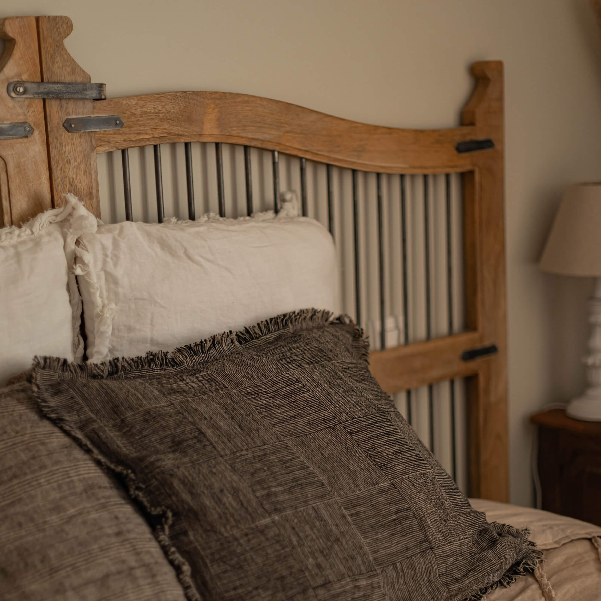 Schlafzimmer mit naturfarbenem Holz-Kopfteil sowie beigen und braunen Kissen für eine gemütliche Atmosphäre
