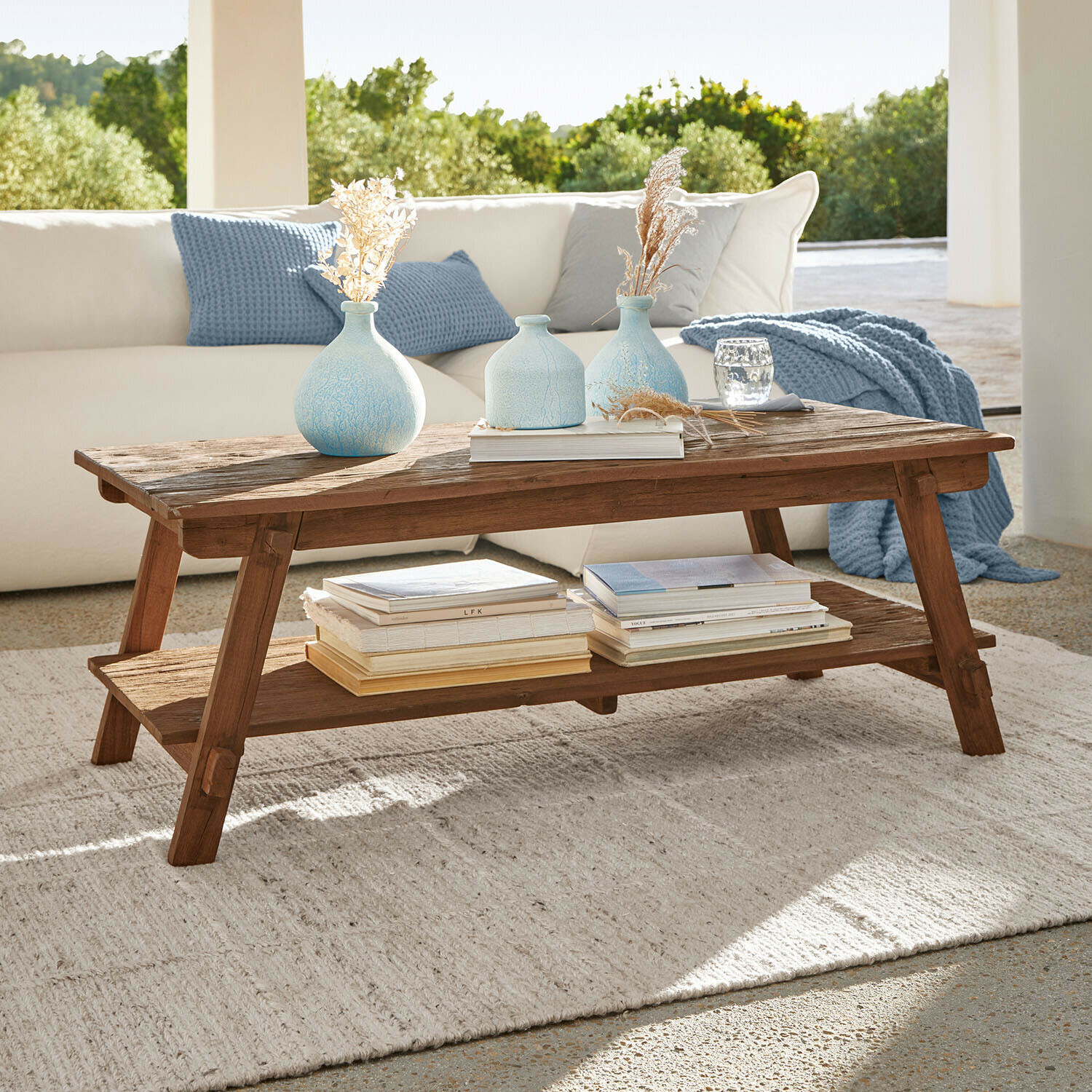 Couchtisch aus Mangoholz in Natur mit Ablage, dekoriert mit blauen Vasen und Büchern