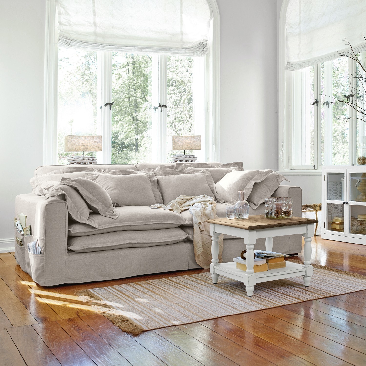 Beiges Stoffsofa mit Kissen und weissem Couchtisch auf Holzboden in hellem Wohnzimmer