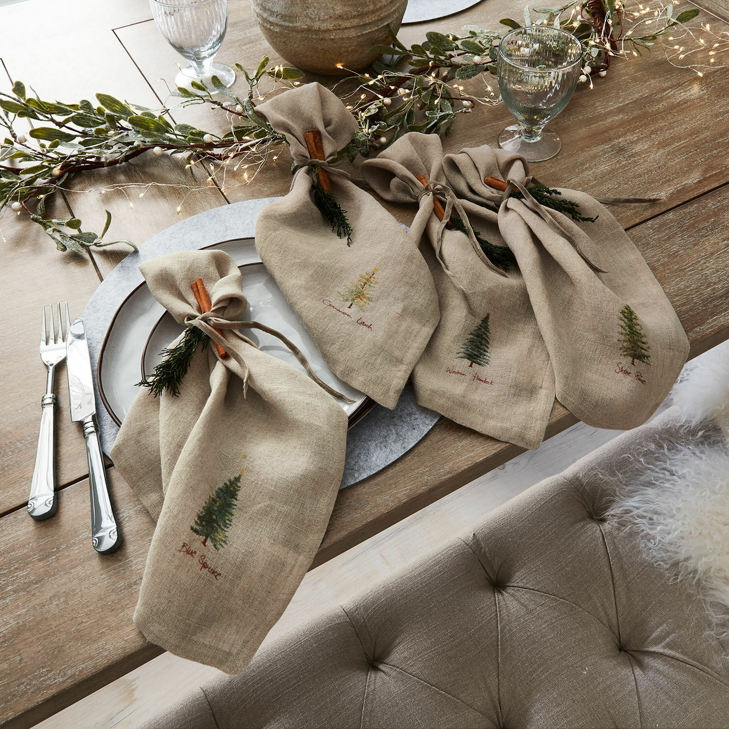Servietten 4er Set Jarrier Beige Leinenservietten mit Baum-Motiven und Zimtdekoration auf rustikalem Holztisch