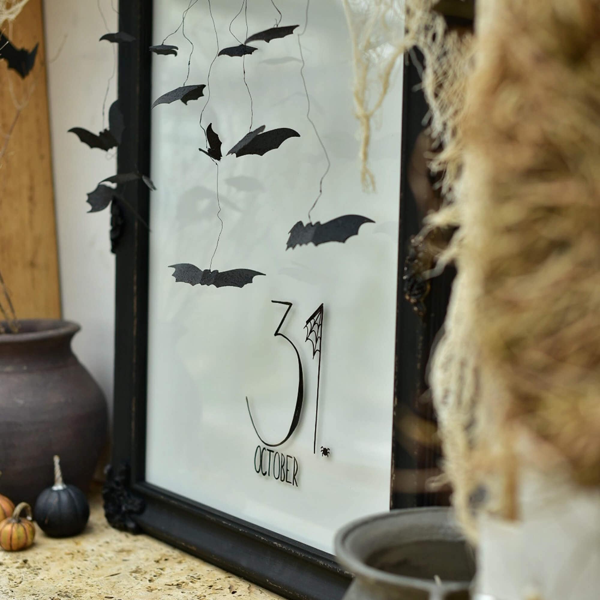 Halloween-Dekoration mit schwarzen Papierfledermäusen und Schriftzug 31. Oktober im Rahmen