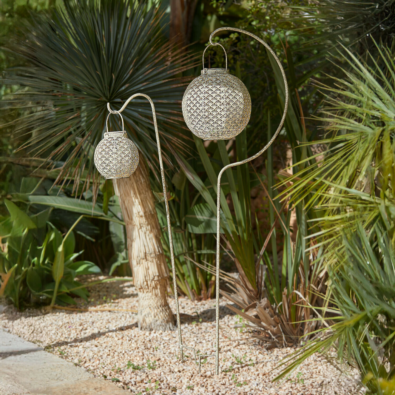 Gartenstab 2er Set Omirah Dekorative Gartenlaternen aus Metall in Antikgold auf Ständern zwischen grünen Pflanzen