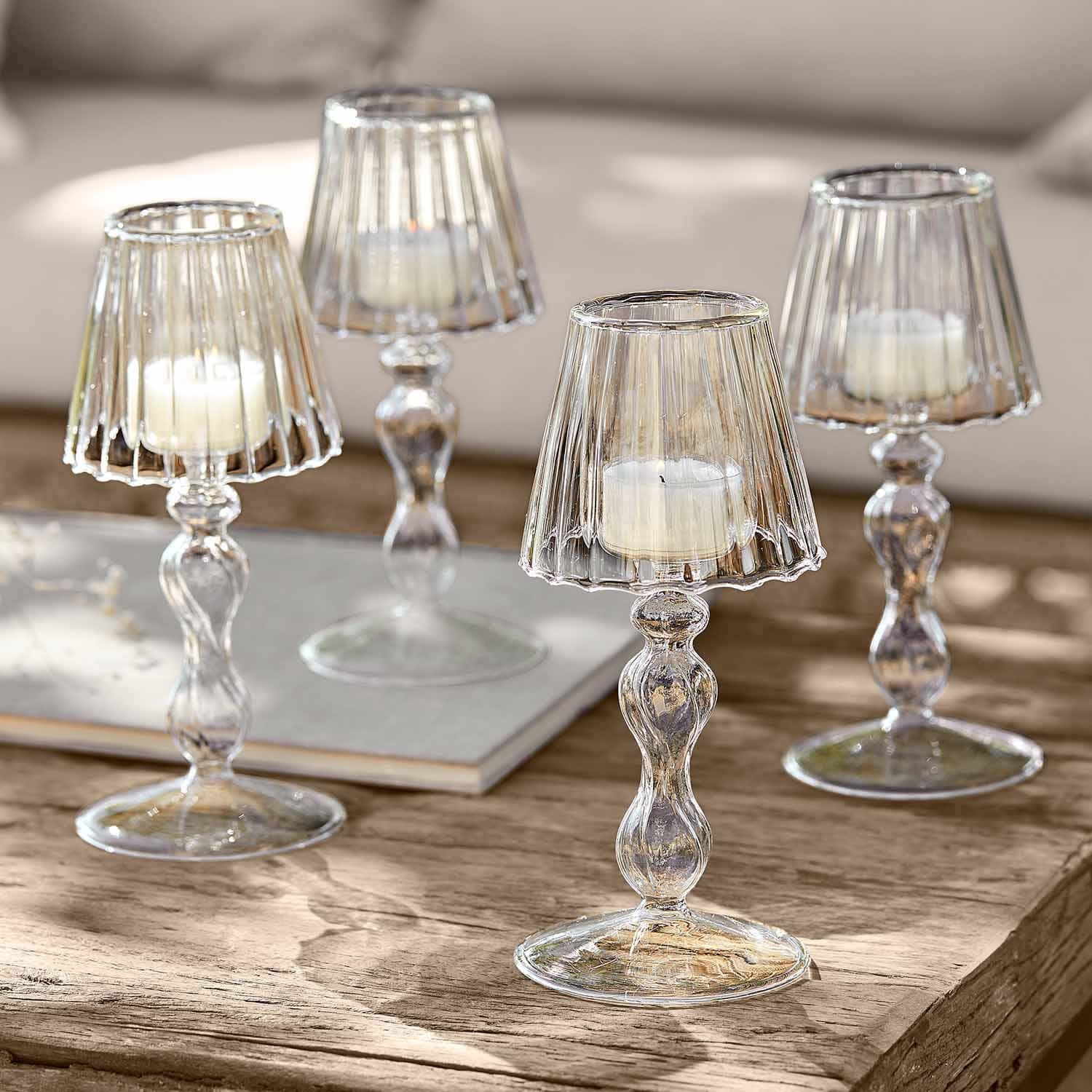 Transparente Glas-Kerzenhalter mit weissen Kerzen auf Holztisch als Wohnaccessoire