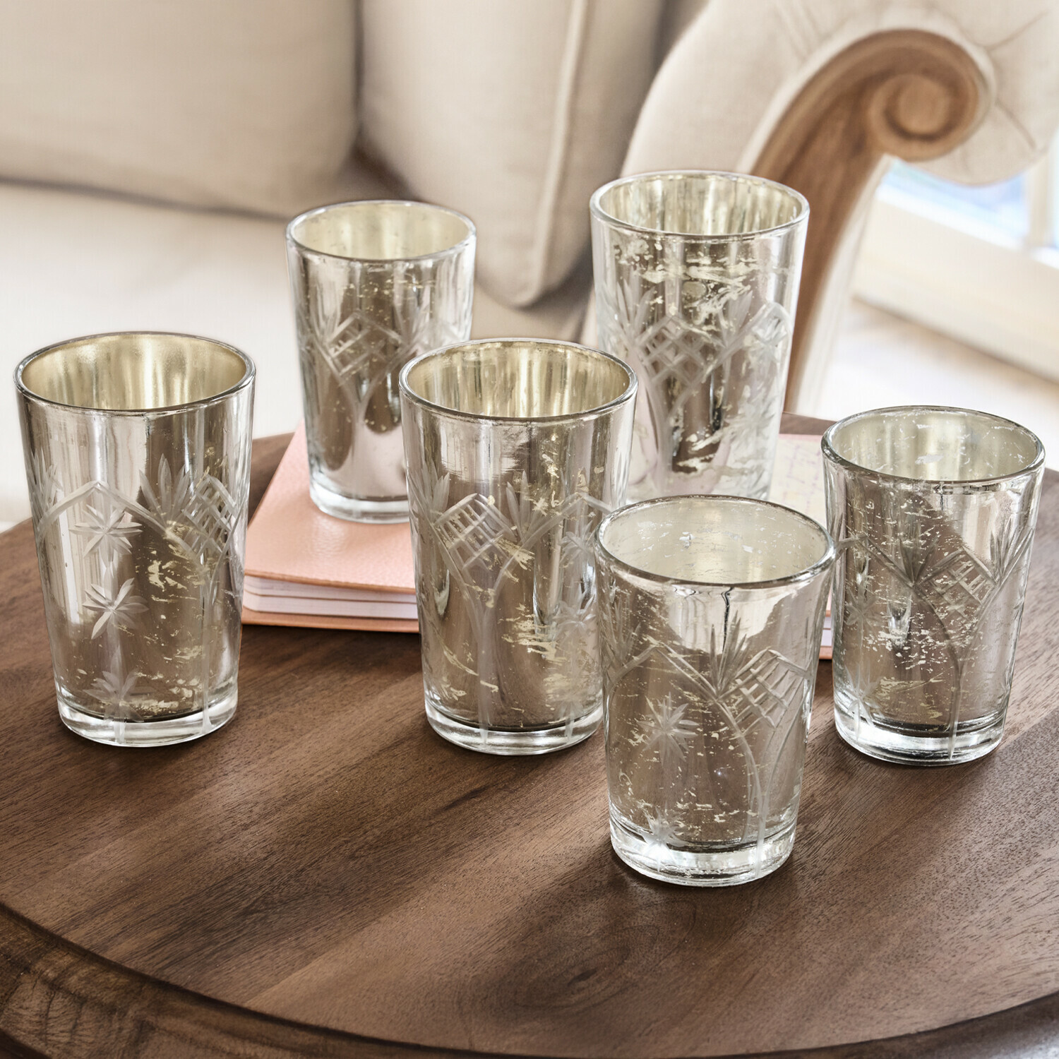 Set mit sechs gravierten Glas-Teelichthaltern mit silberner Innenbeschichtung auf Holztisch