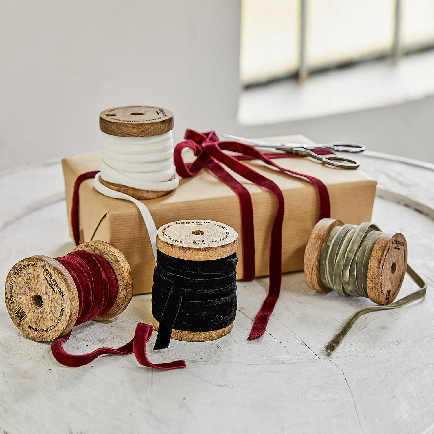 Samtband 4er Set Hilary Set aus Holzspulen mit Samtbändern in Weiss, Rot, Schwarz und Oliv auf Tisch mit Geschenk