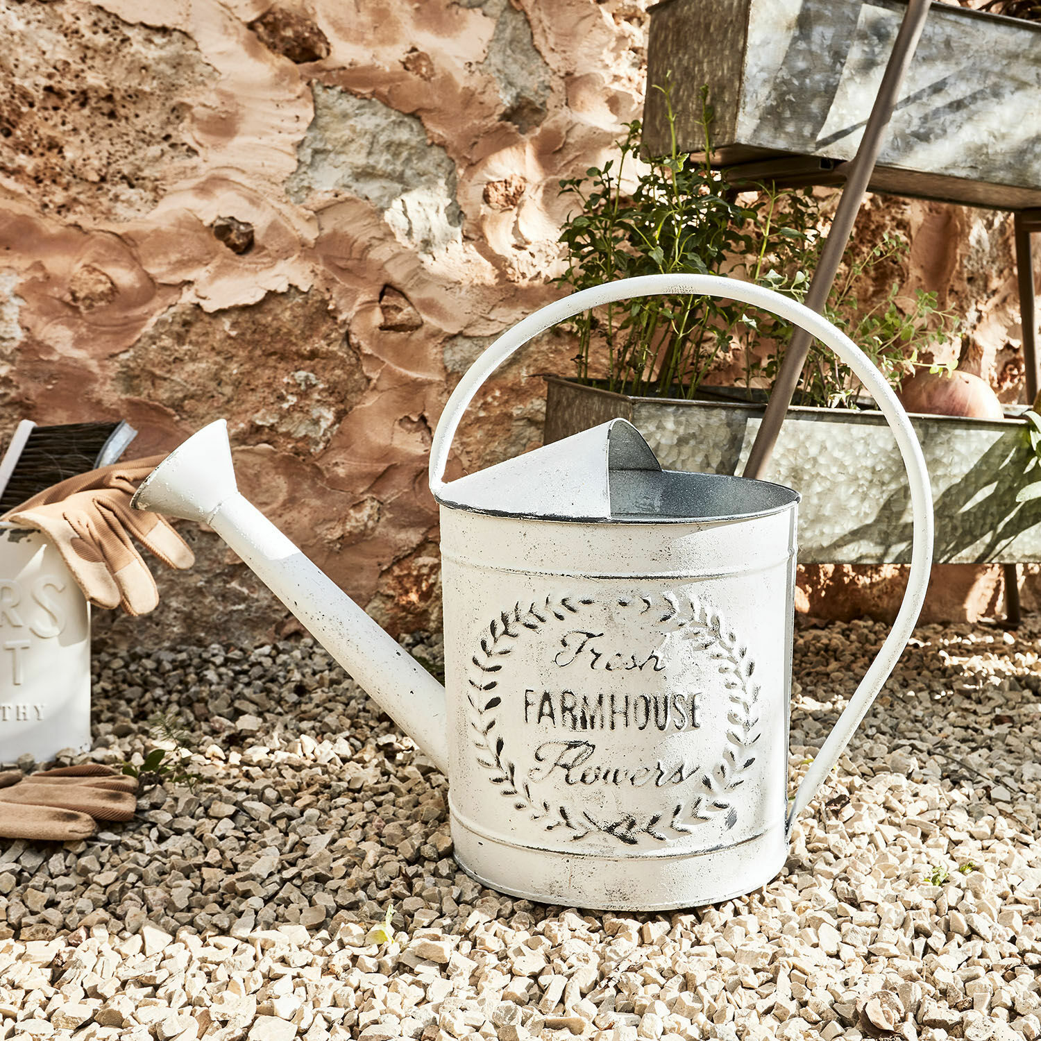 Giesskanne Farmhouse Weisse Metall-Giesskanne mit Farmhouse-Schriftzug auf Kiesboden zum Giessen von Pflanzen im Garten