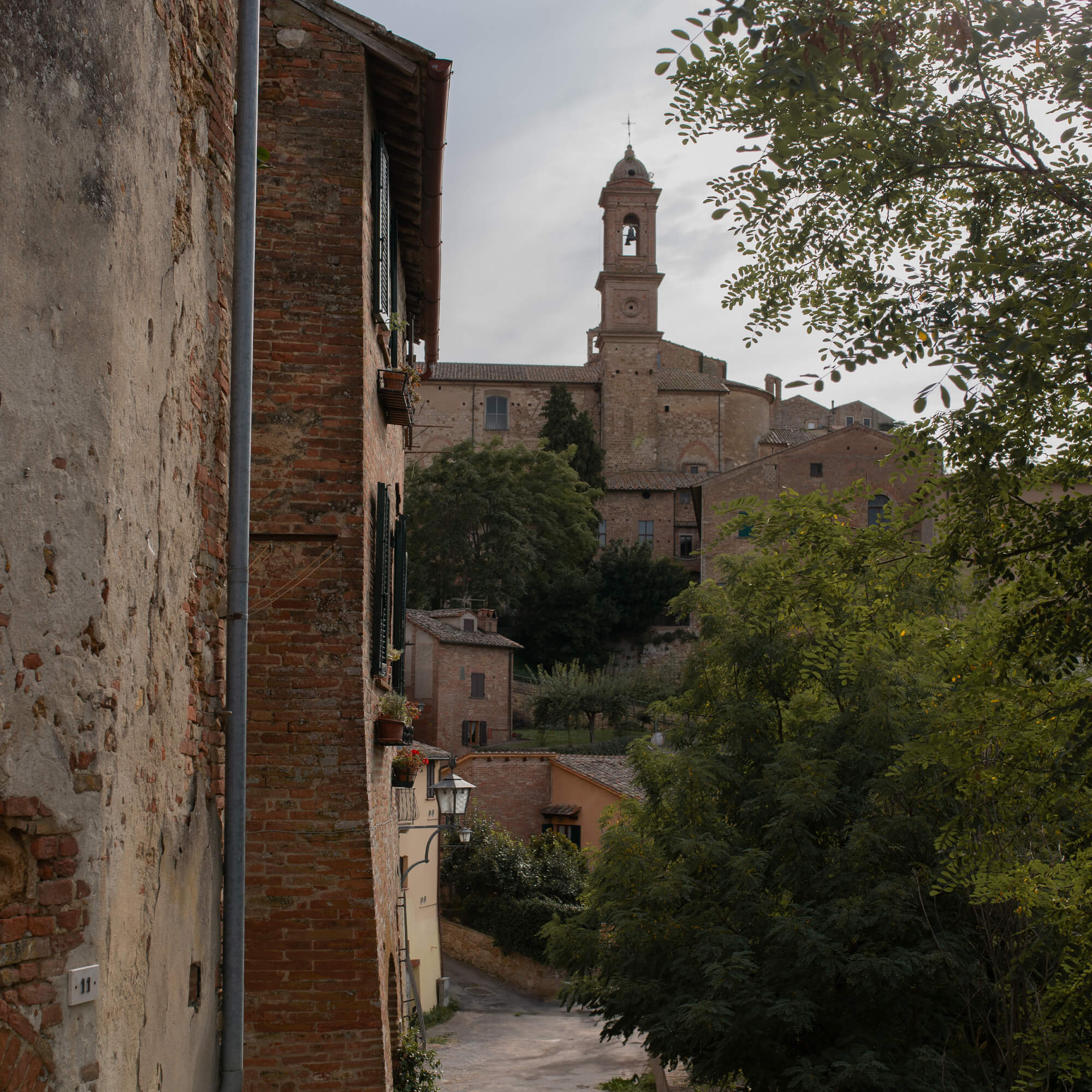 Blick auf eine alte Gasse mit Backsteinbauten und Kirchturm im Hintergrund, Natur und Architektur