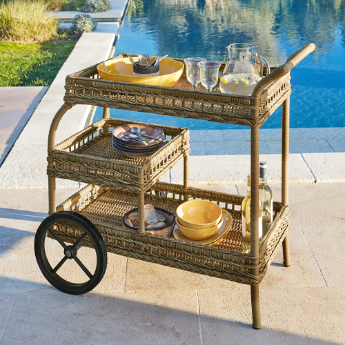 Barwagen aus natürlichem Rattan mit zwei grossen Rädern, ideal zum Servieren von Getränken im Freien.