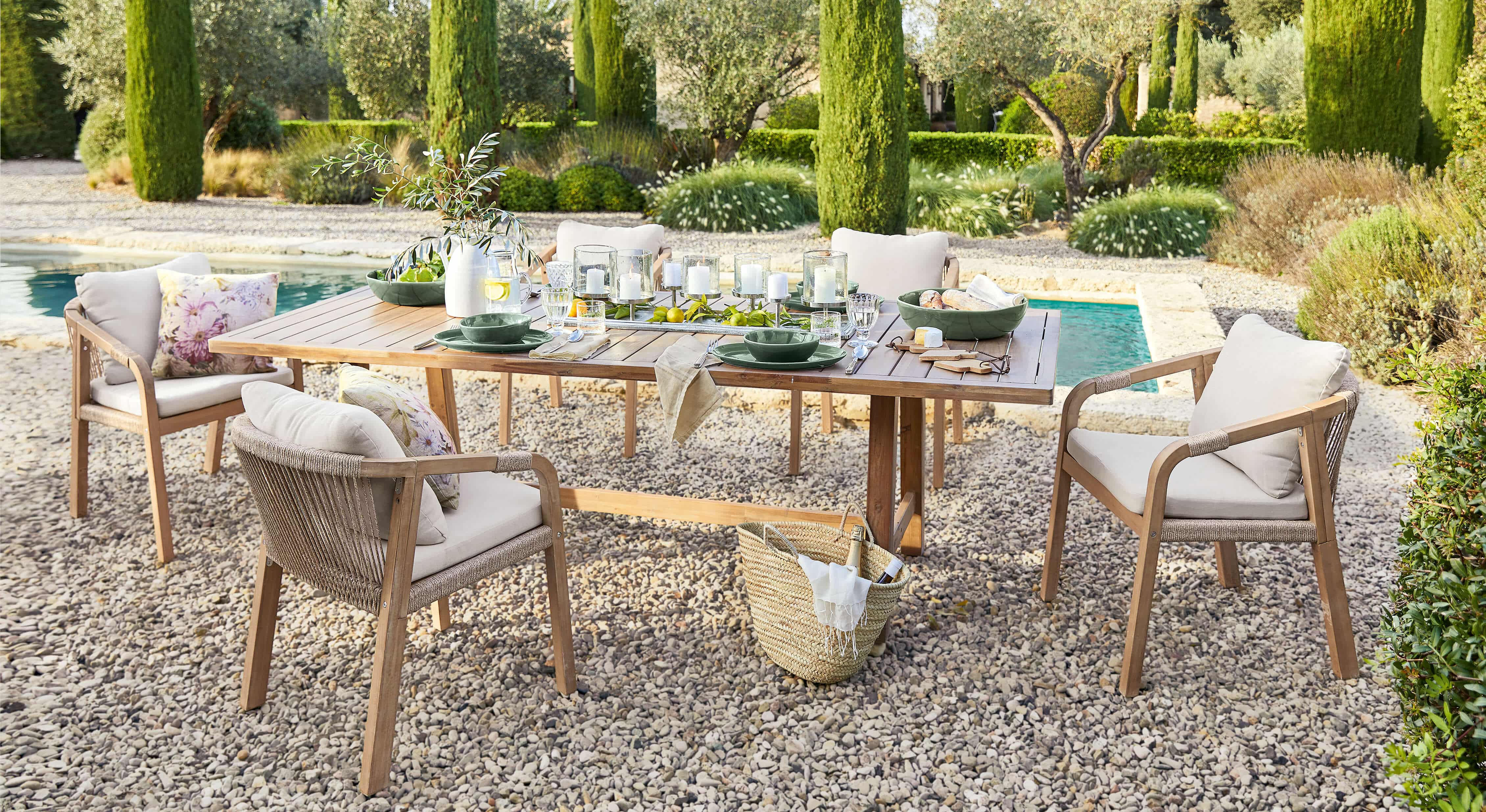 Gartenmöbel-Set mit Holztisch und beigen Stühlen auf Kieselstein-Terrasse neben dem Schwimmbecken