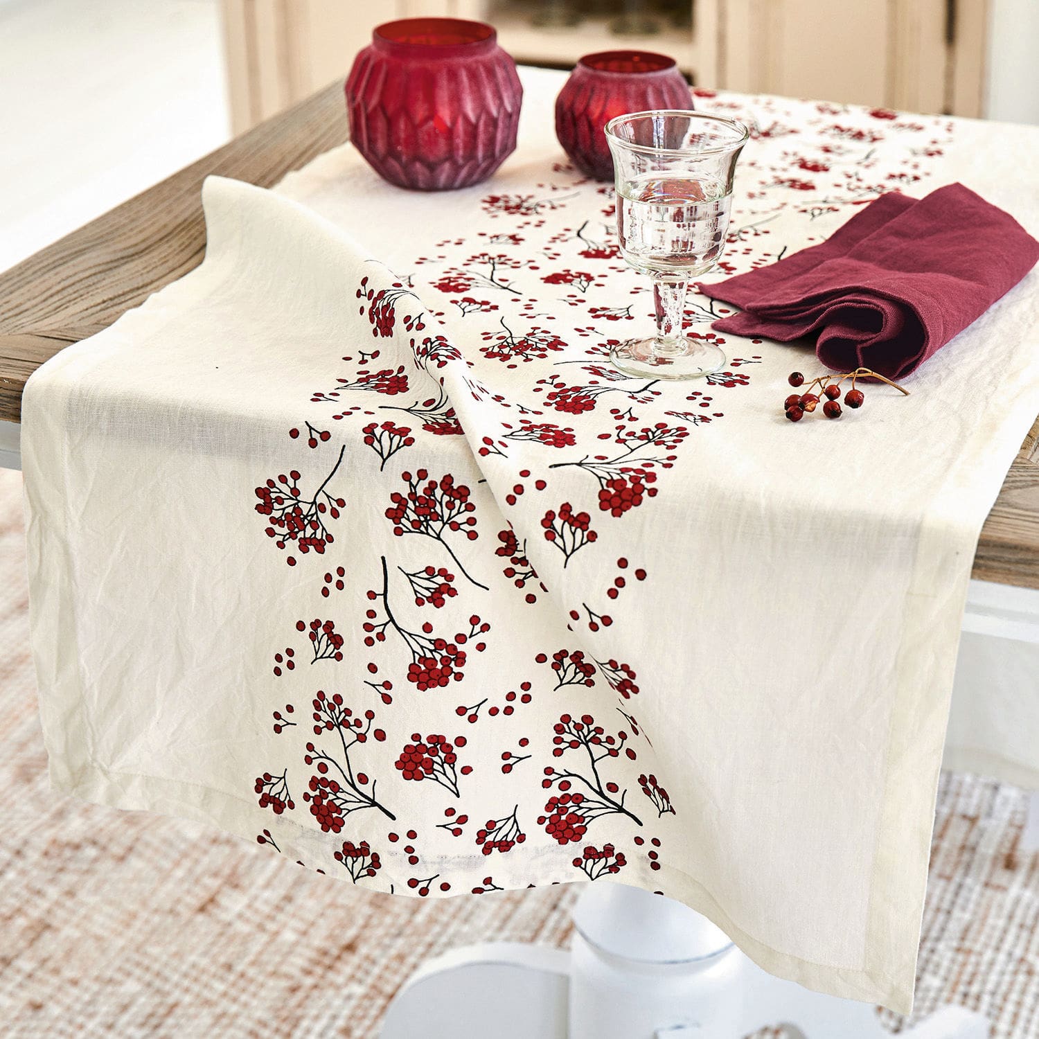 Tischläufer Vestré Leinentischdecke in Creme mit rotem Beerenmuster auf Holztisch mit Dekorationen