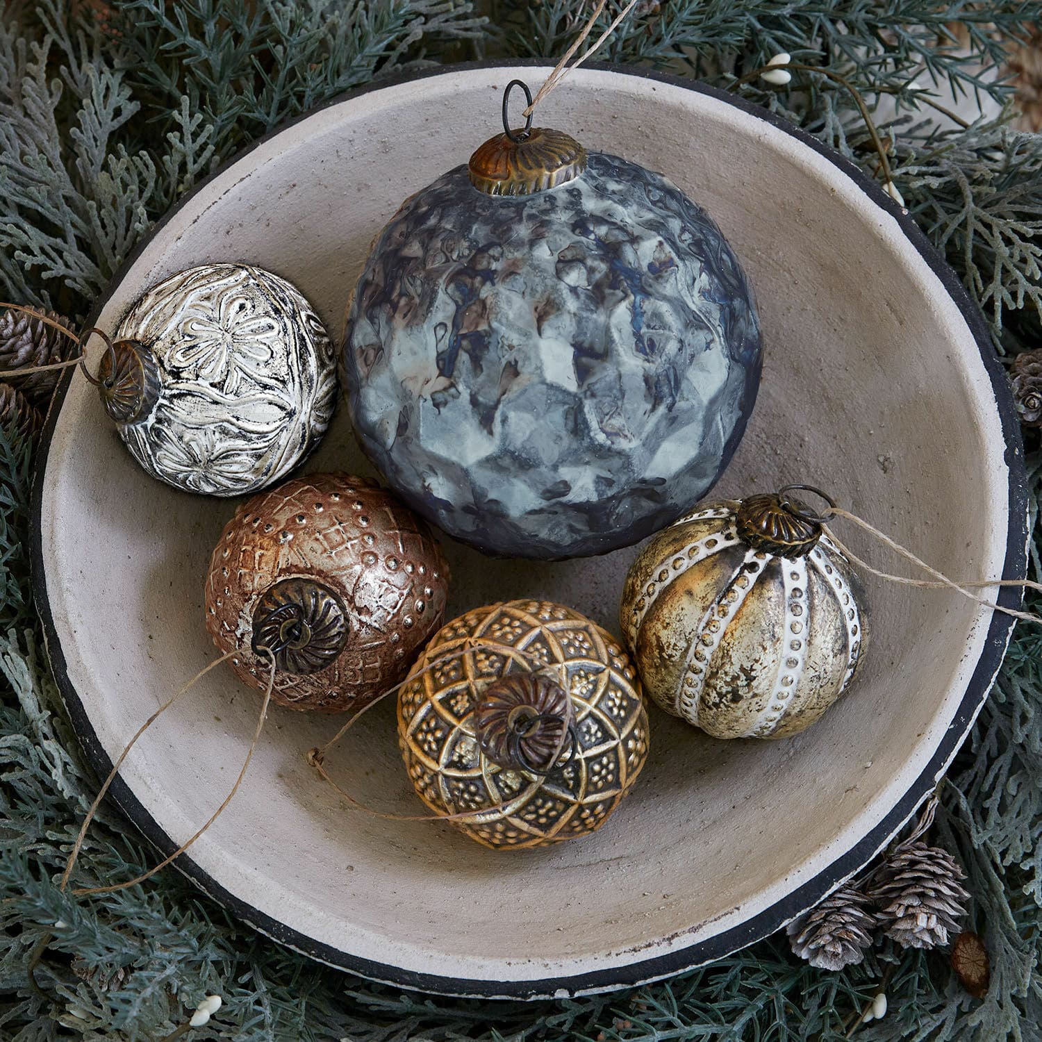 Weihnachtsschmuck 5er Set Jilian Dekorative Weihnachtskugeln aus Metall in verschiedenen Farben in einer Keramikschale auf grünem Hintergrund