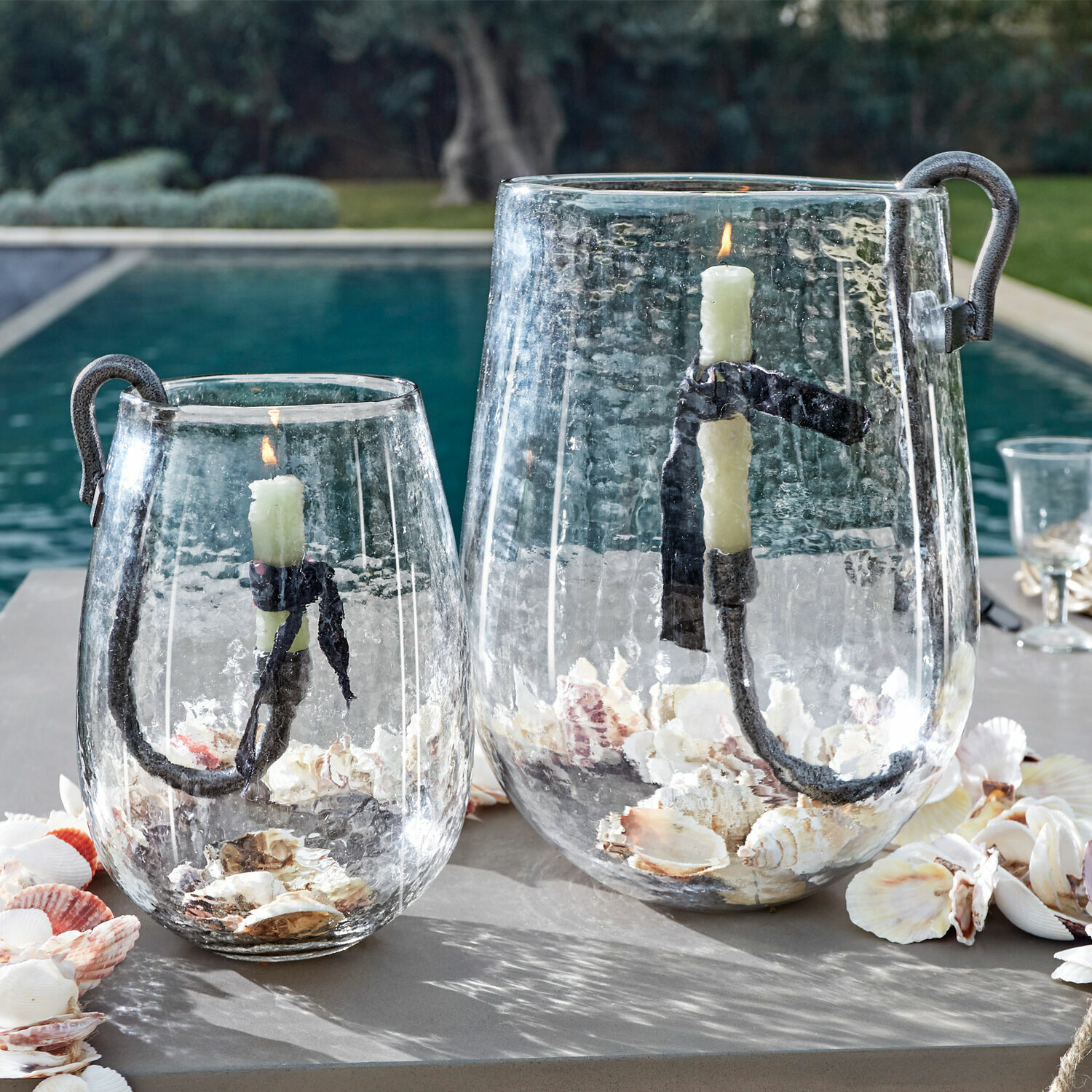 Glaslaternen mit Metallgriff und weißen Kerzen, gefüllt mit Muscheln, Outdoor-Dekoration