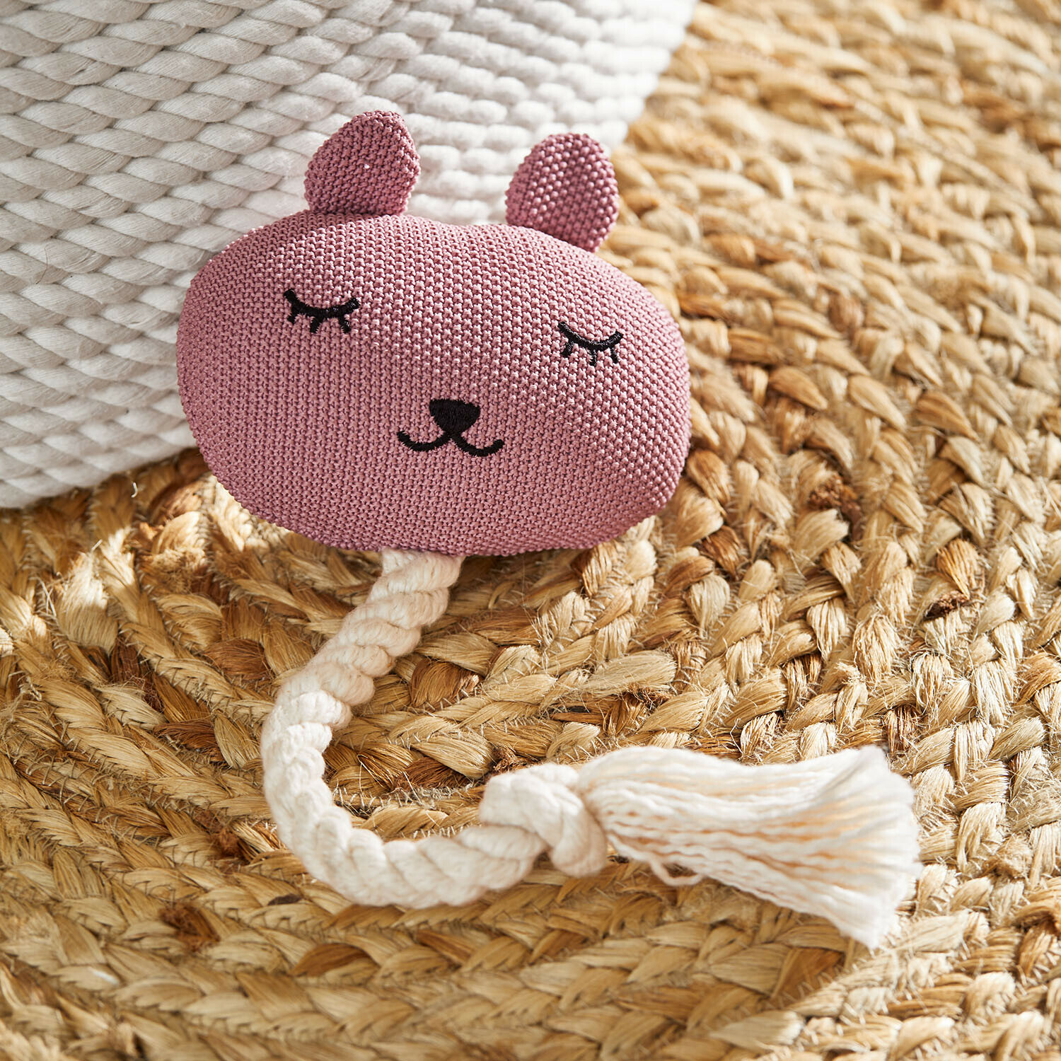 Katzenspielzeug Miezmo Rosa gestricktes Tier-Spielzeug mit weissem Seil auf geflochtenem Naturteppich