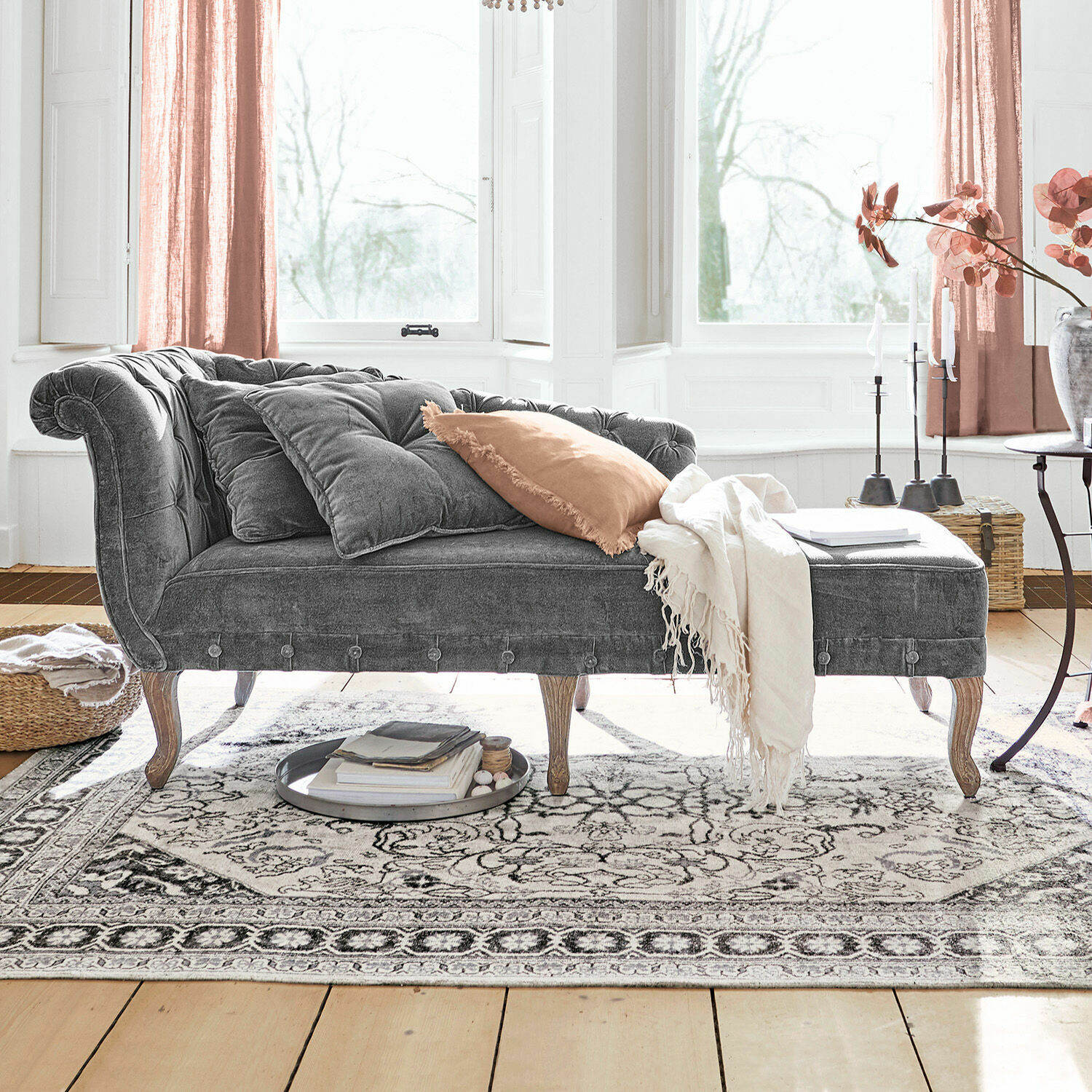 Chaiselongue Viviani Graue Samt-Chaiselongue mit Holzbeinen und hellen Kissen im hellen Wohnzimmer