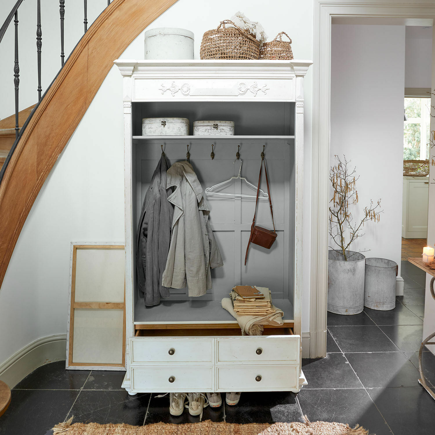 Garderobe Étourville Weisser Holz-Garderobenschrank mit Haken, Schubladen und dekorativen Körben im hellen Flur