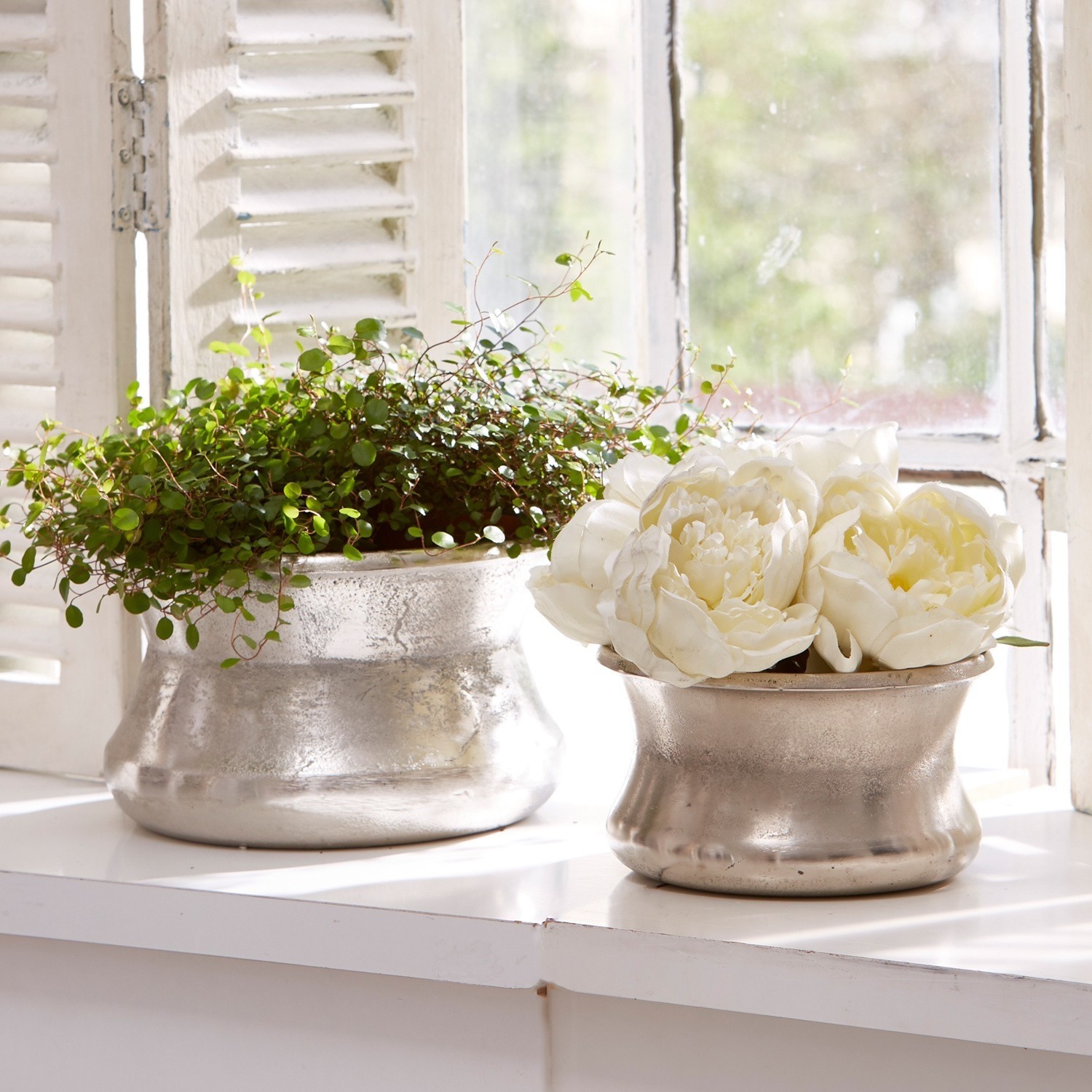 Vase 2er Set Riona Zwei silberne Metallblumentöpfe auf der Fensterbank mit grüner Pflanze und weissen Dekoblumen