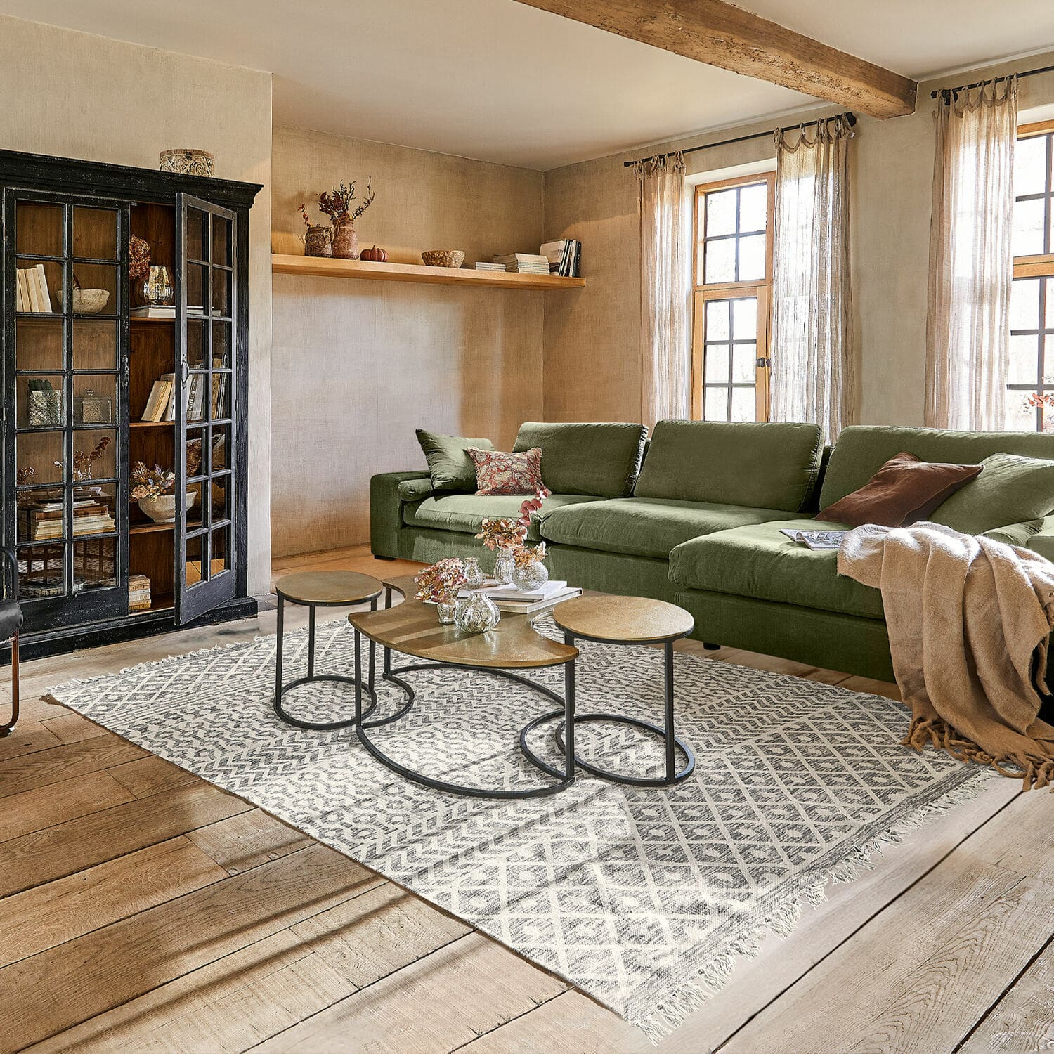 In- & Outdoor-Teppich Champigny Gemütliches Wohnzimmer mit grünem Stoffsofa, Holzboden, modernem Teppich und Metall-Couchtischen