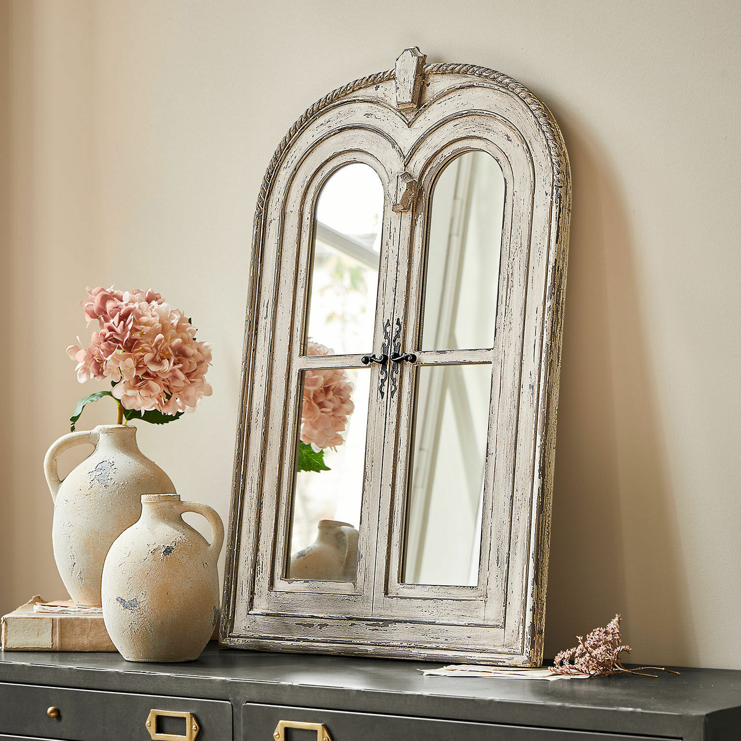 Rustikaler Spiegel aus Holz im weissen Shabby-Look auf schwarzem Sideboard mit Blumen