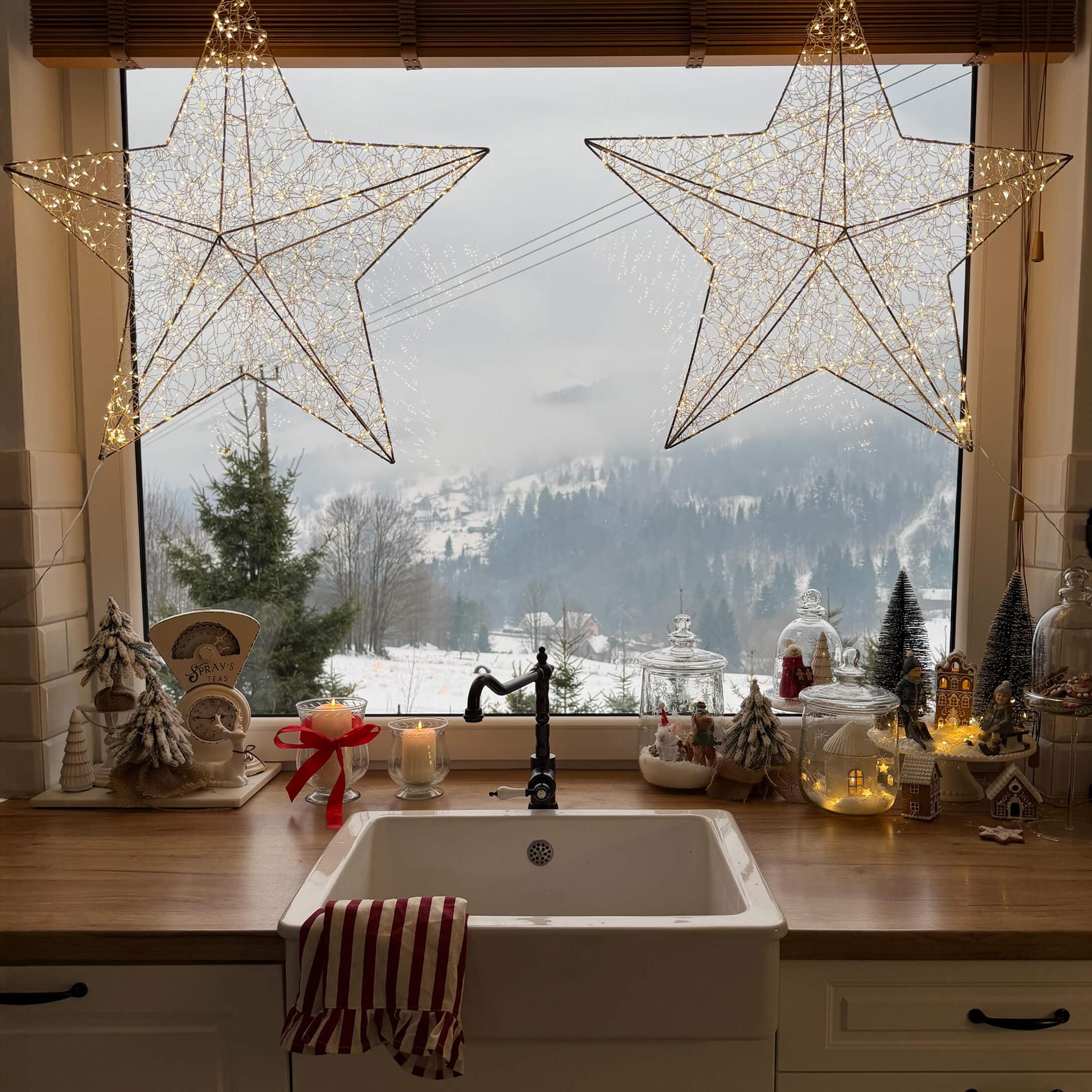 Küche mit weissem Spülbecken, Holzarbeitsfläche, Weihnachtsdekorationen und winterlicher Aussicht