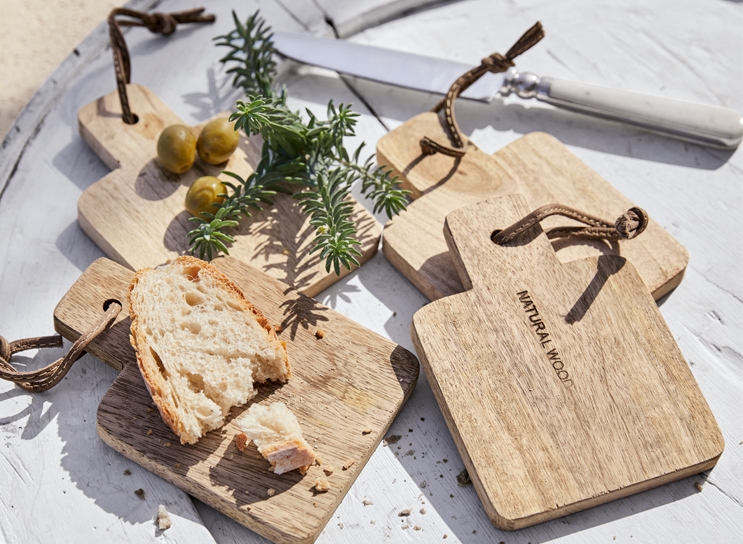 Set aus natürlichen Holz-Schneidebrettern mit Brot und Oliven auf weissem Tisch im mediterranen Stil