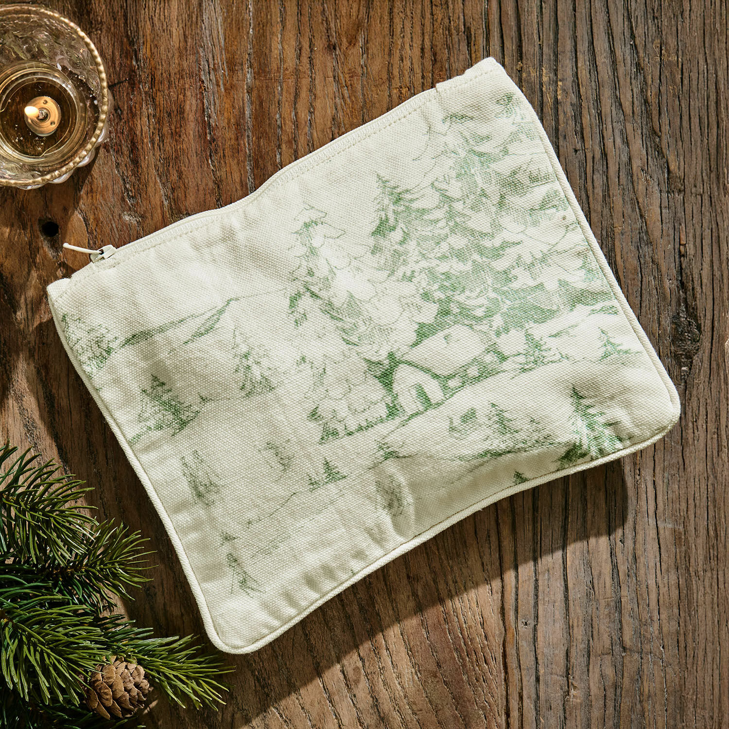 Täschchen Norathia Beige Baumwoll-Kosmetiktasche mit grünem Waldmotiv auf Holztisch liegend